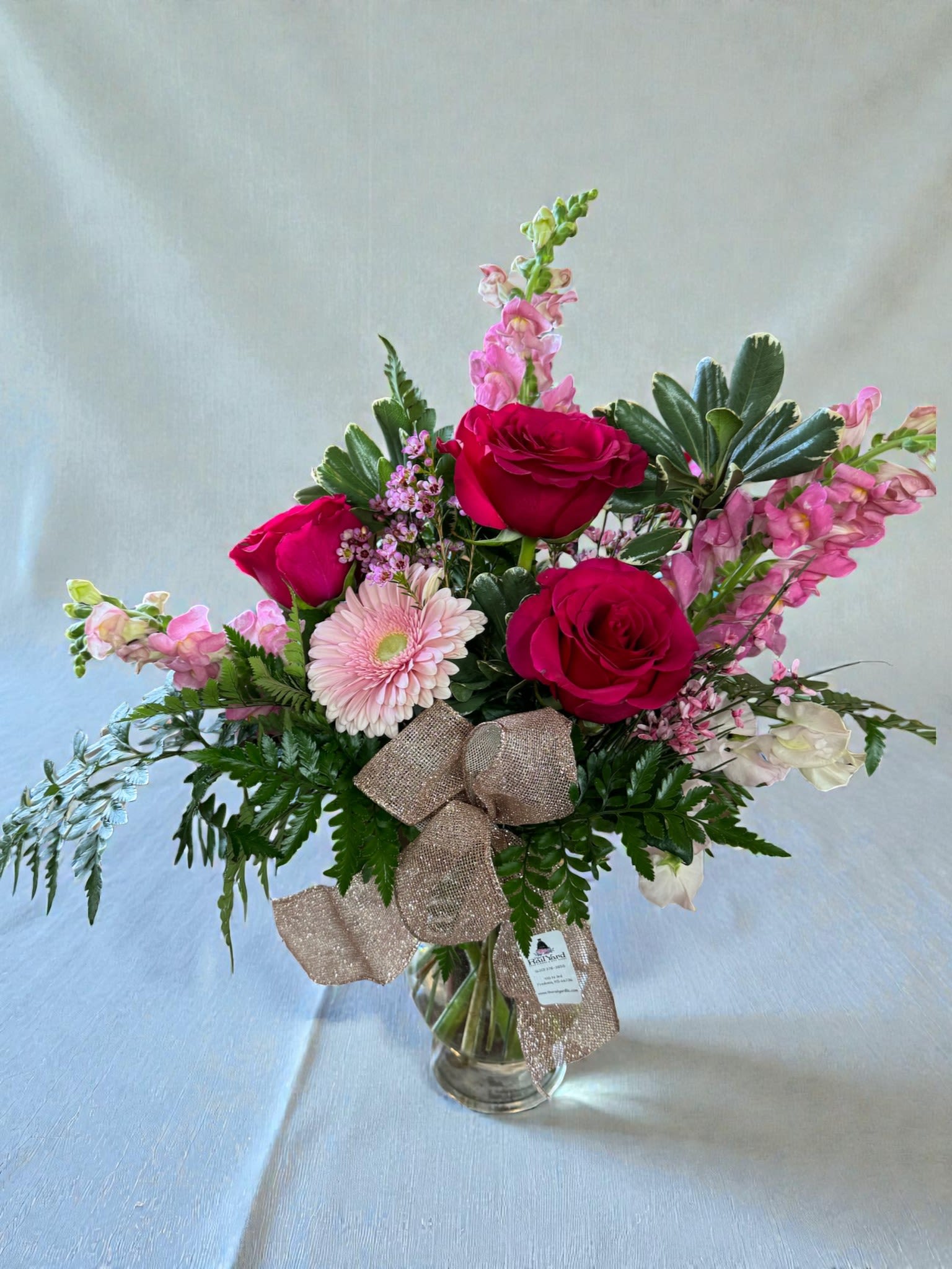 Bouquet of red roses and pink flowers in a glass vase with a ribbon