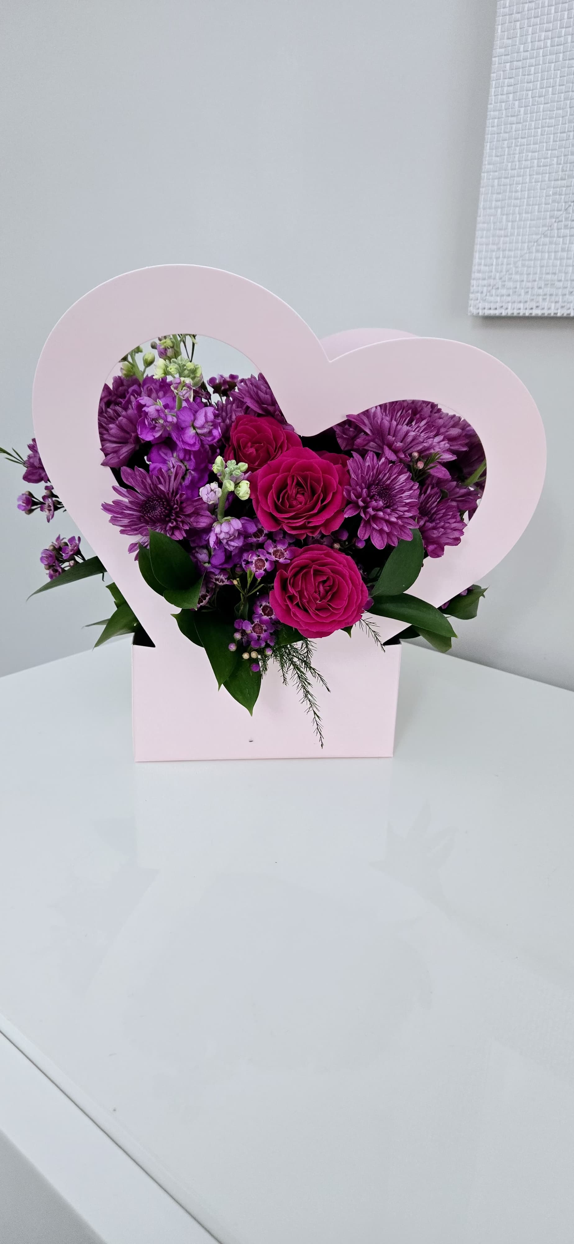 Pink heart-shaped box with purple flowers and magenta roses