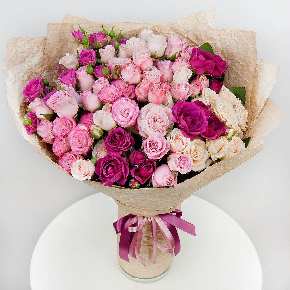 Bouquet of pink and white roses wrapped in beige paper with a ribbon