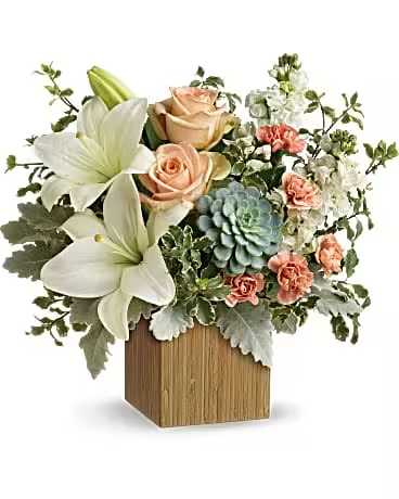 Flower arrangement with white lilies, peach roses, and a blue succulent in a wooden vase
