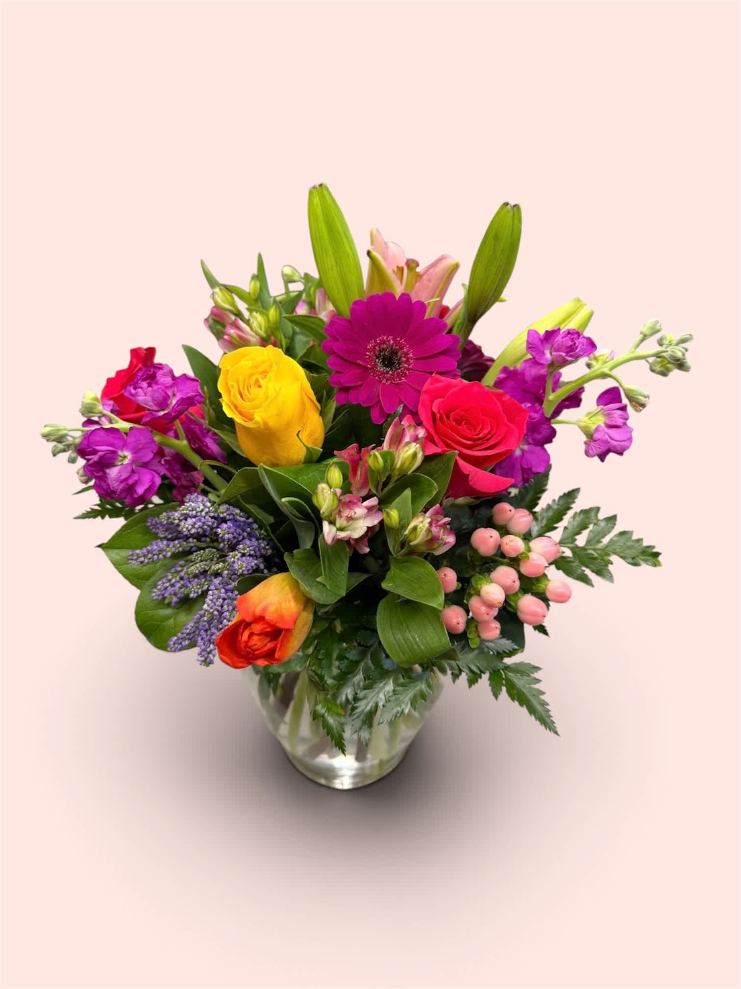 Mixed bouquet of bright flowers in a clear glass vase