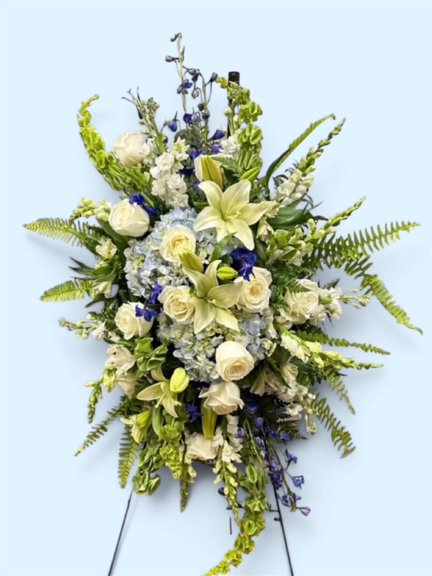 Standing floral spray with white lilies, roses, and blue flowers