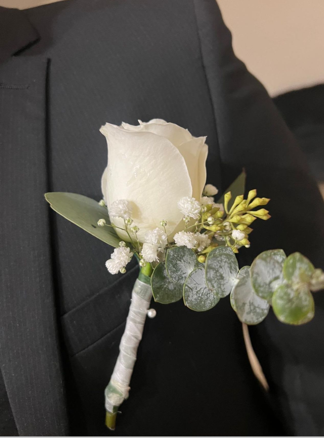 White rose boutonniere with small white filler flowers and eucalyptus