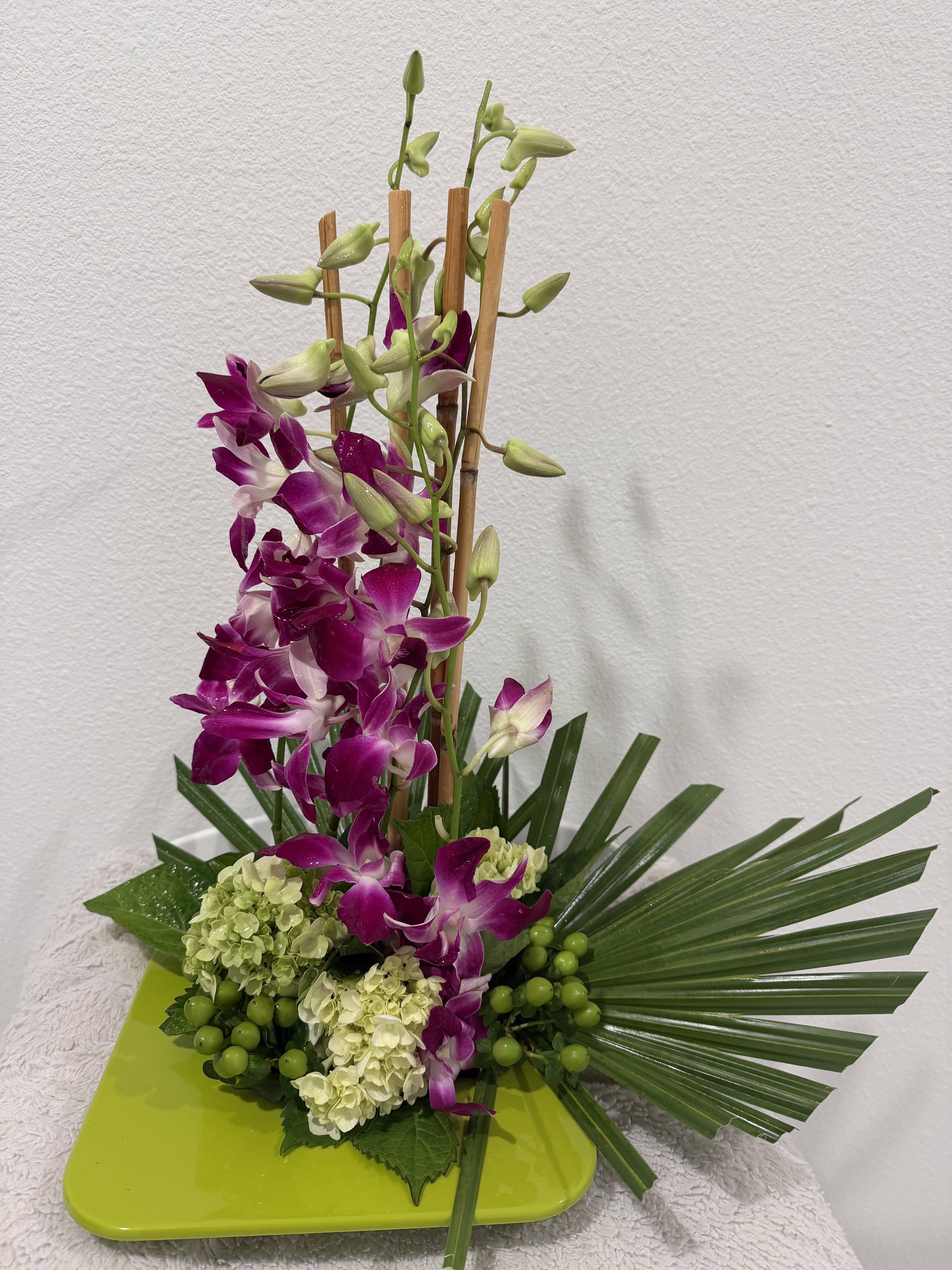 Purple orchids arranged with pale hydrangeas on a green tray
