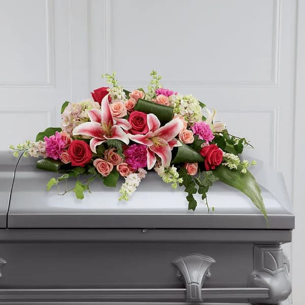 Floral casket spray with pink lilies and red roses