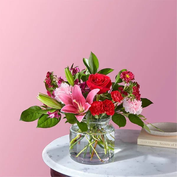 Pink and red mixed bouquet in a clear glass vase on a table