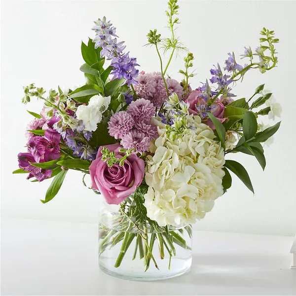Mixed bouquet of pink, white, and purple flowers in a clear glass vase