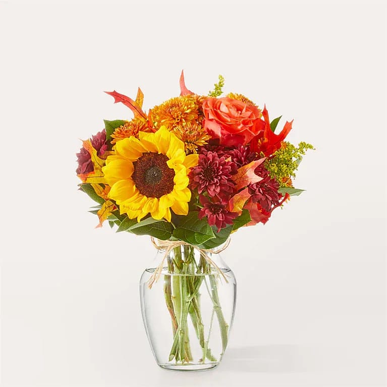 Sunflower and autumn-toned bouquet in a clear glass vase
