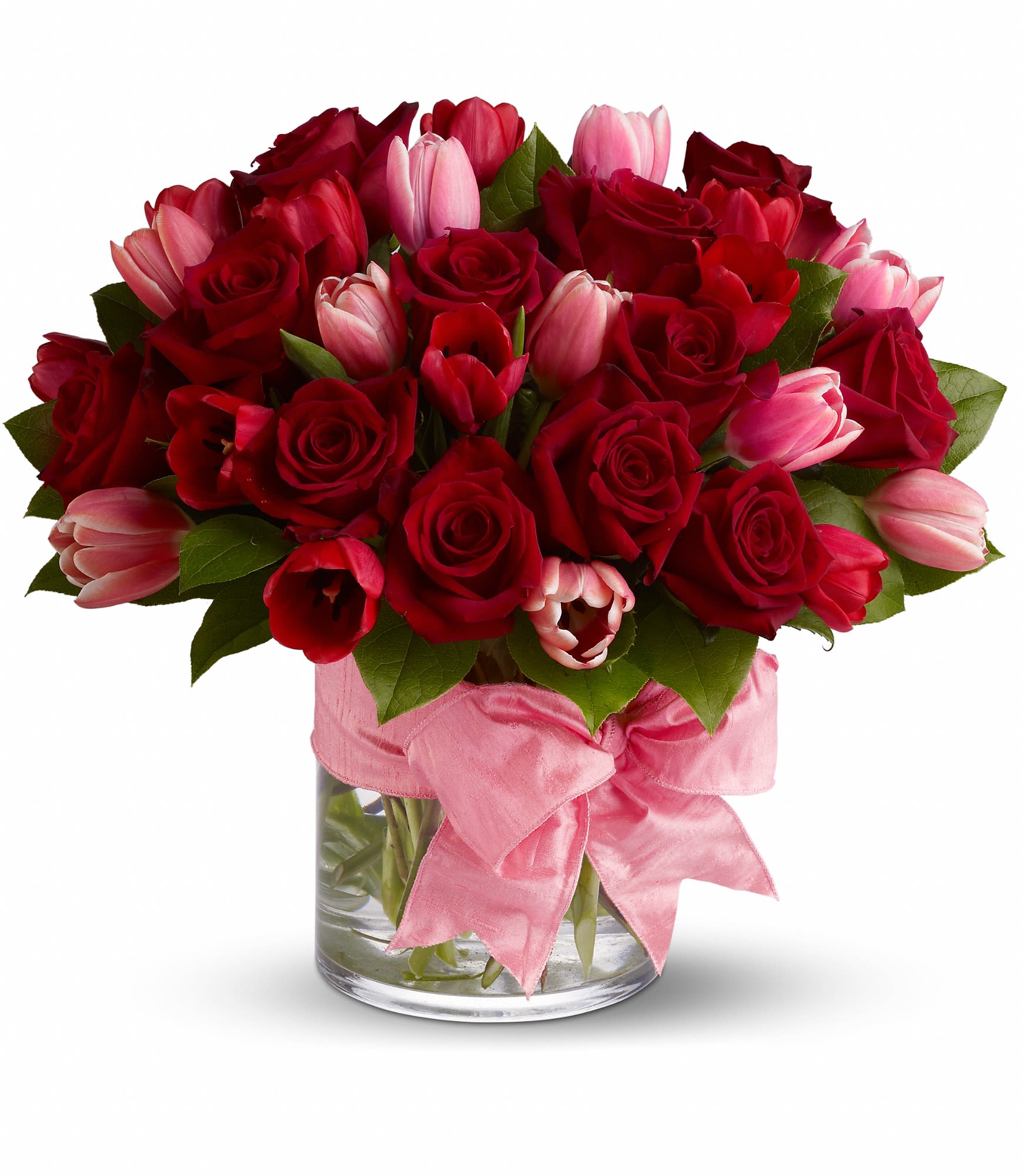 Red roses and pink tulips in a glass vase with a pink ribbon