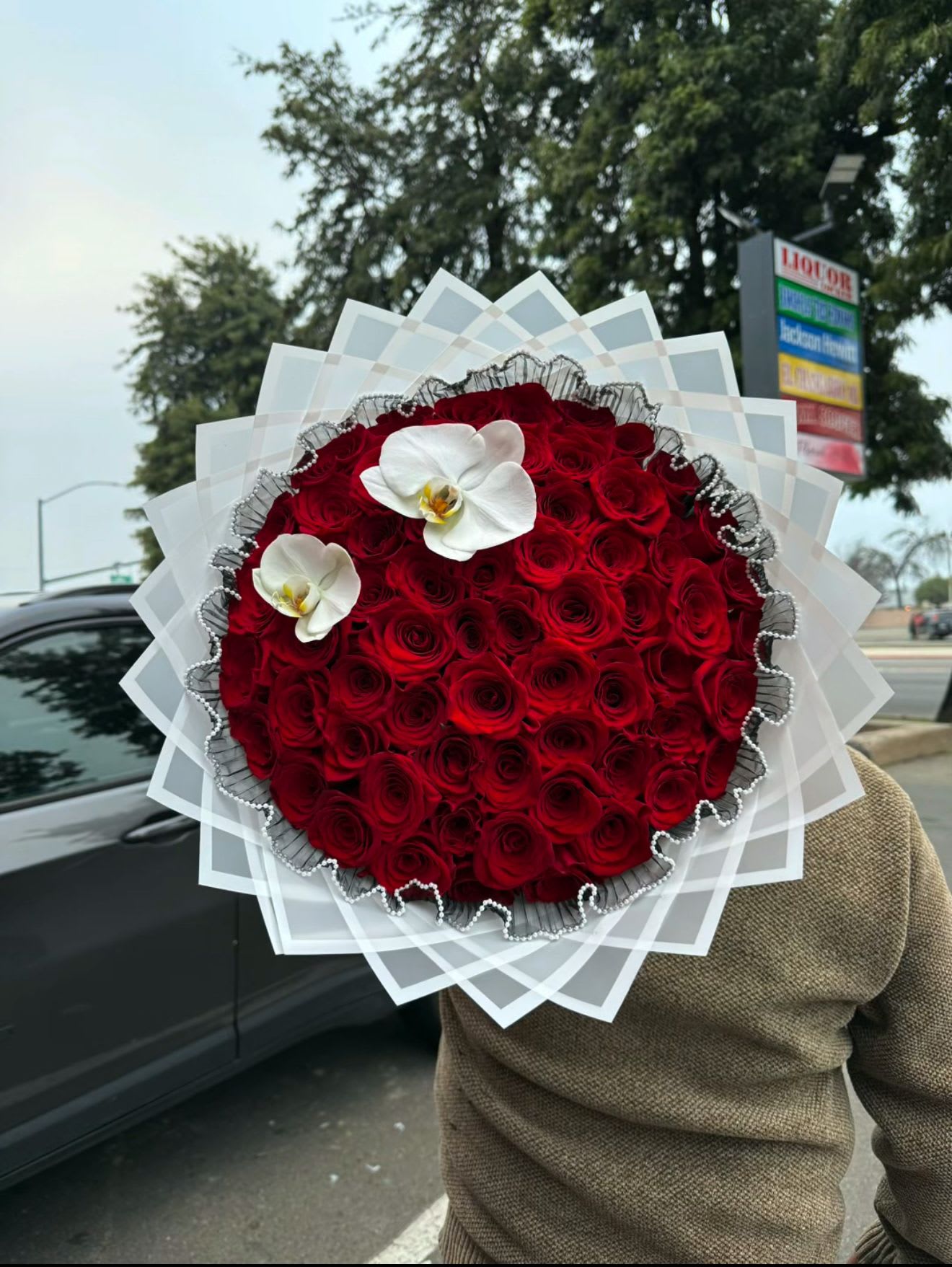 Large round bouquet of red roses with two white orchids