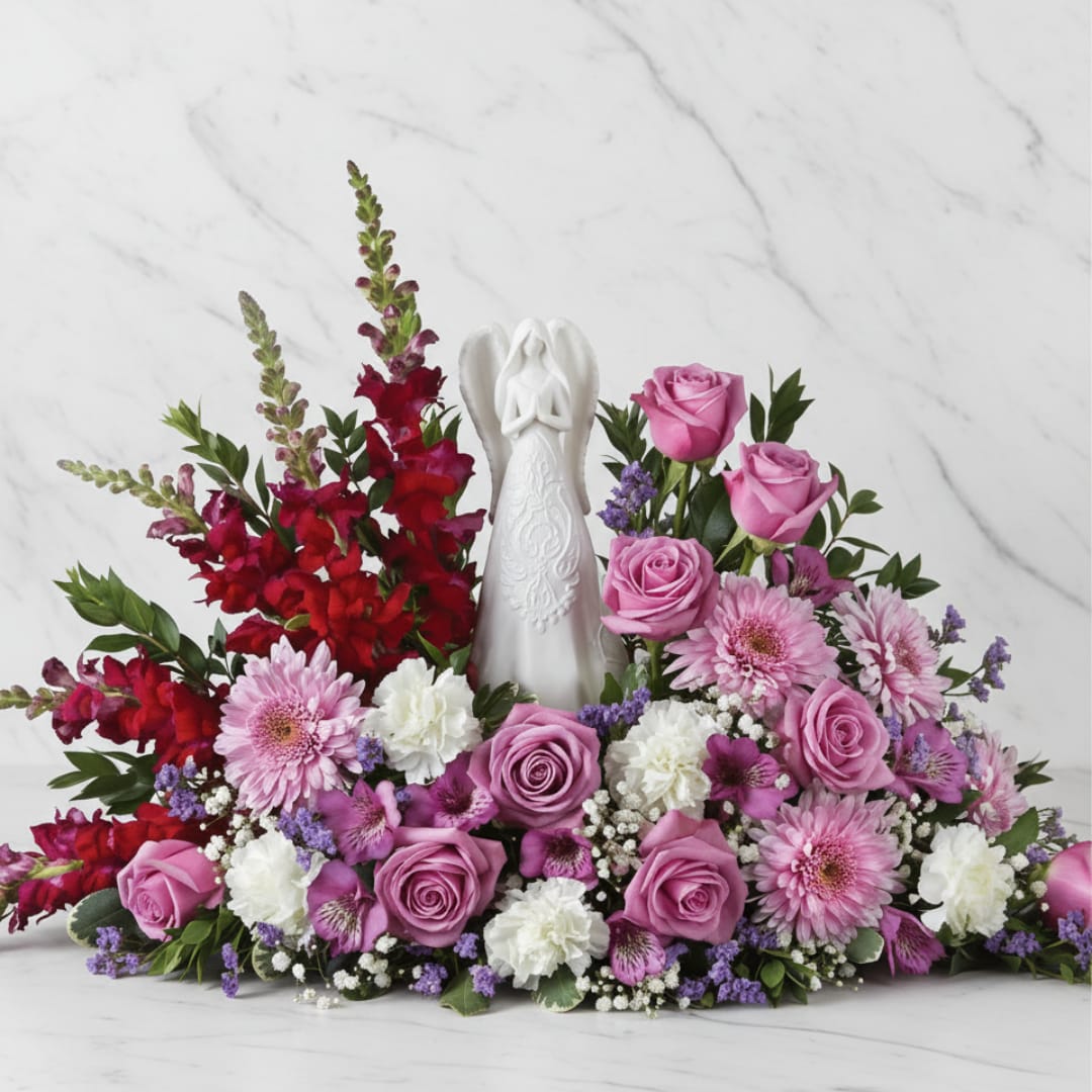 Pink and red floral arrangement with a white angel figurine in the center