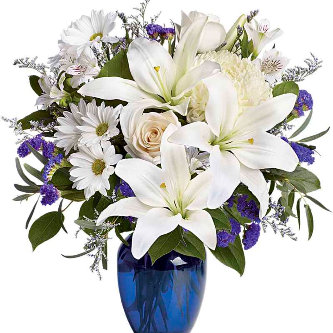 White lilies and daisies arranged in a blue glass vase