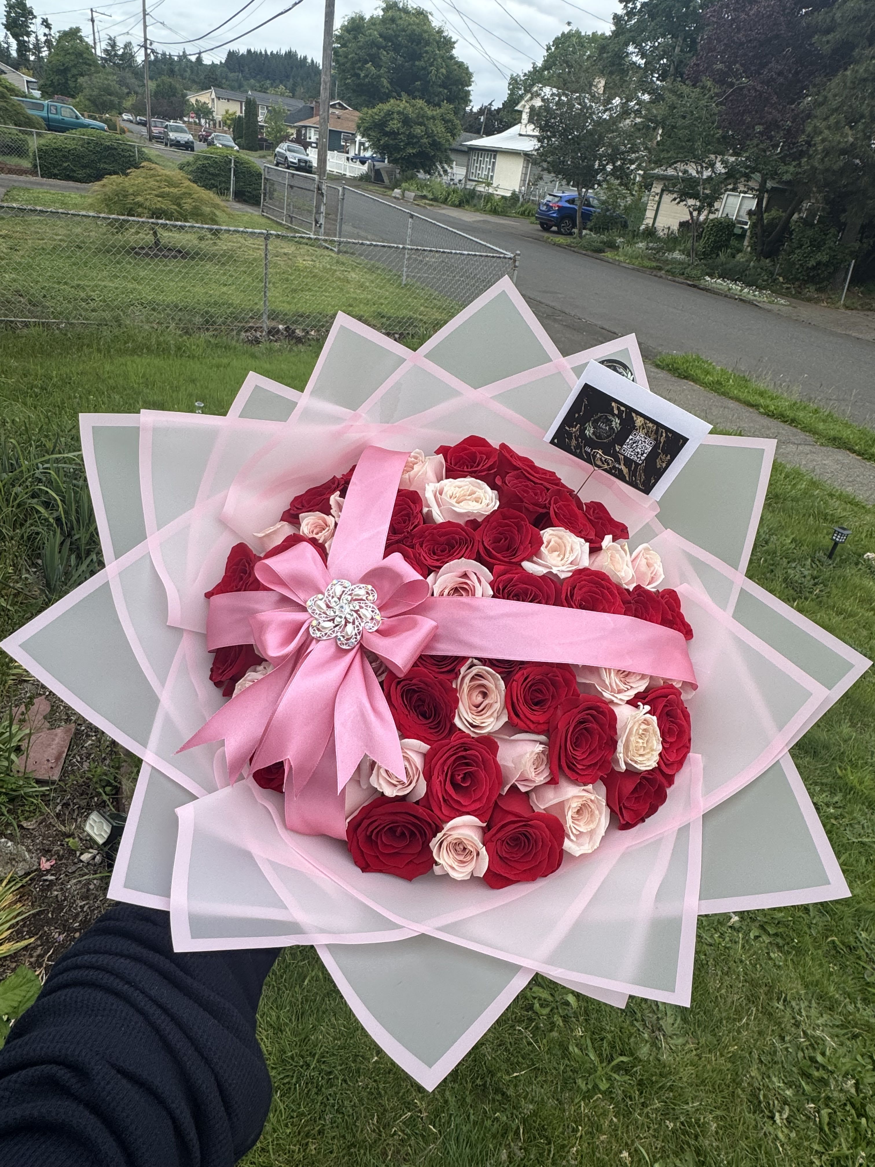 Large bouquet of red and blush roses wrapped in pink paper with a ribbon