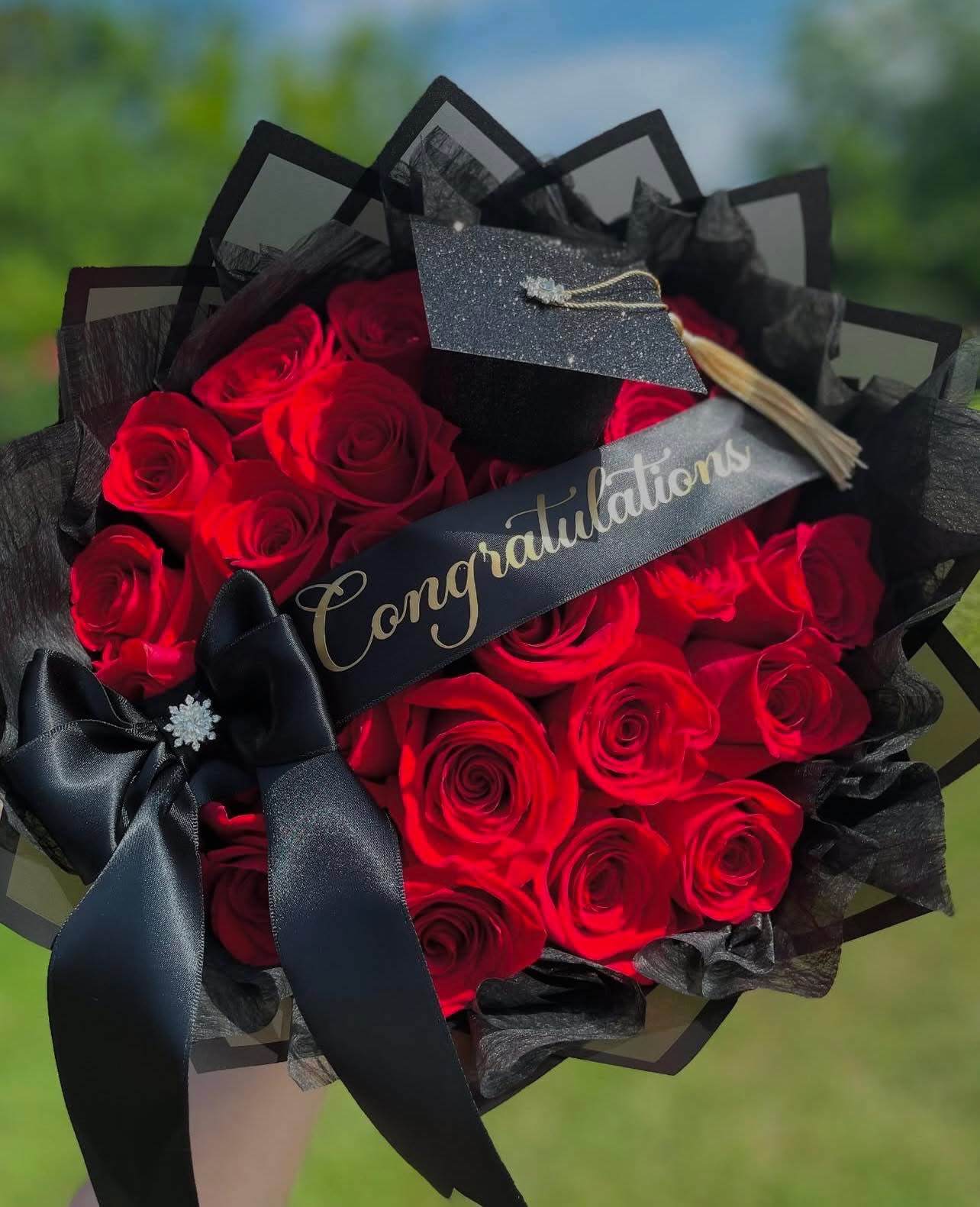 Bouquet of red roses wrapped in black paper with a congratulatory ribbon