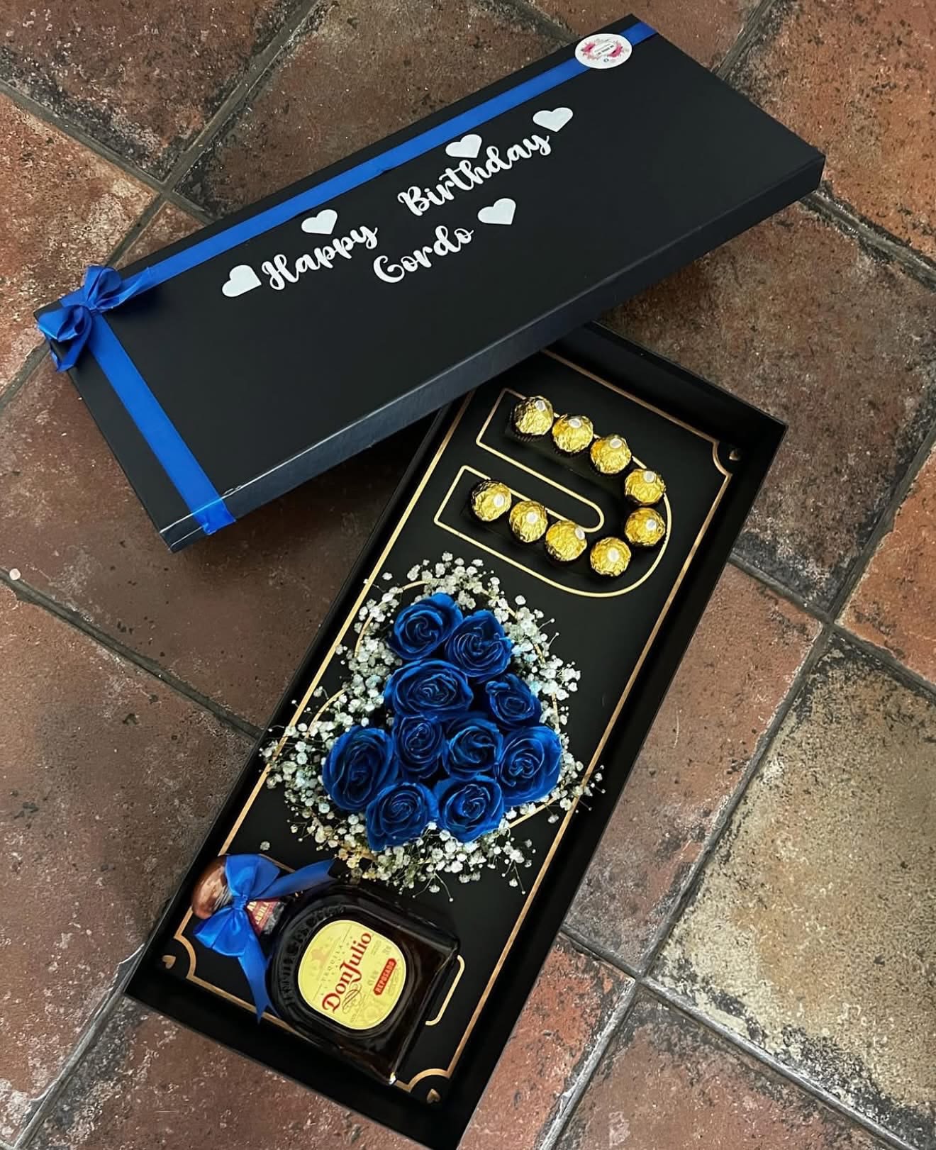 Gift box with blue roses, chocolates, and a bottle of Don Julio