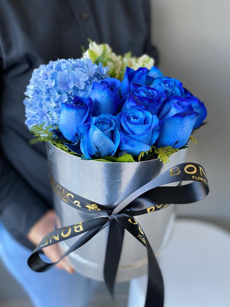 Blue roses and a blue hydrangea bouquet in a silver box with ribbon