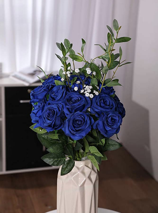 Blue rose bouquet in a white vase with green foliage