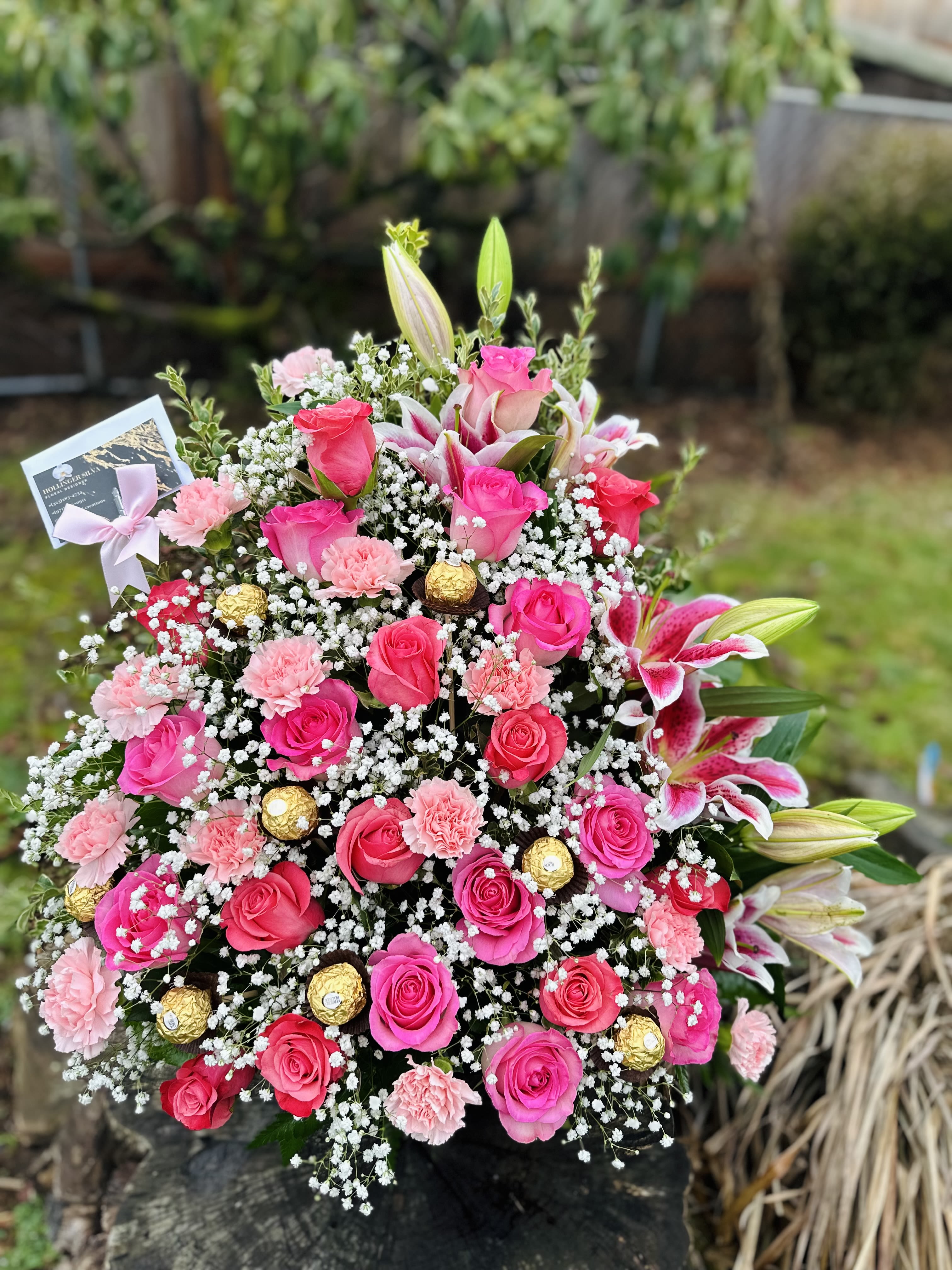 Pink roses and lilies arranged with baby's breath and gold chocolates
