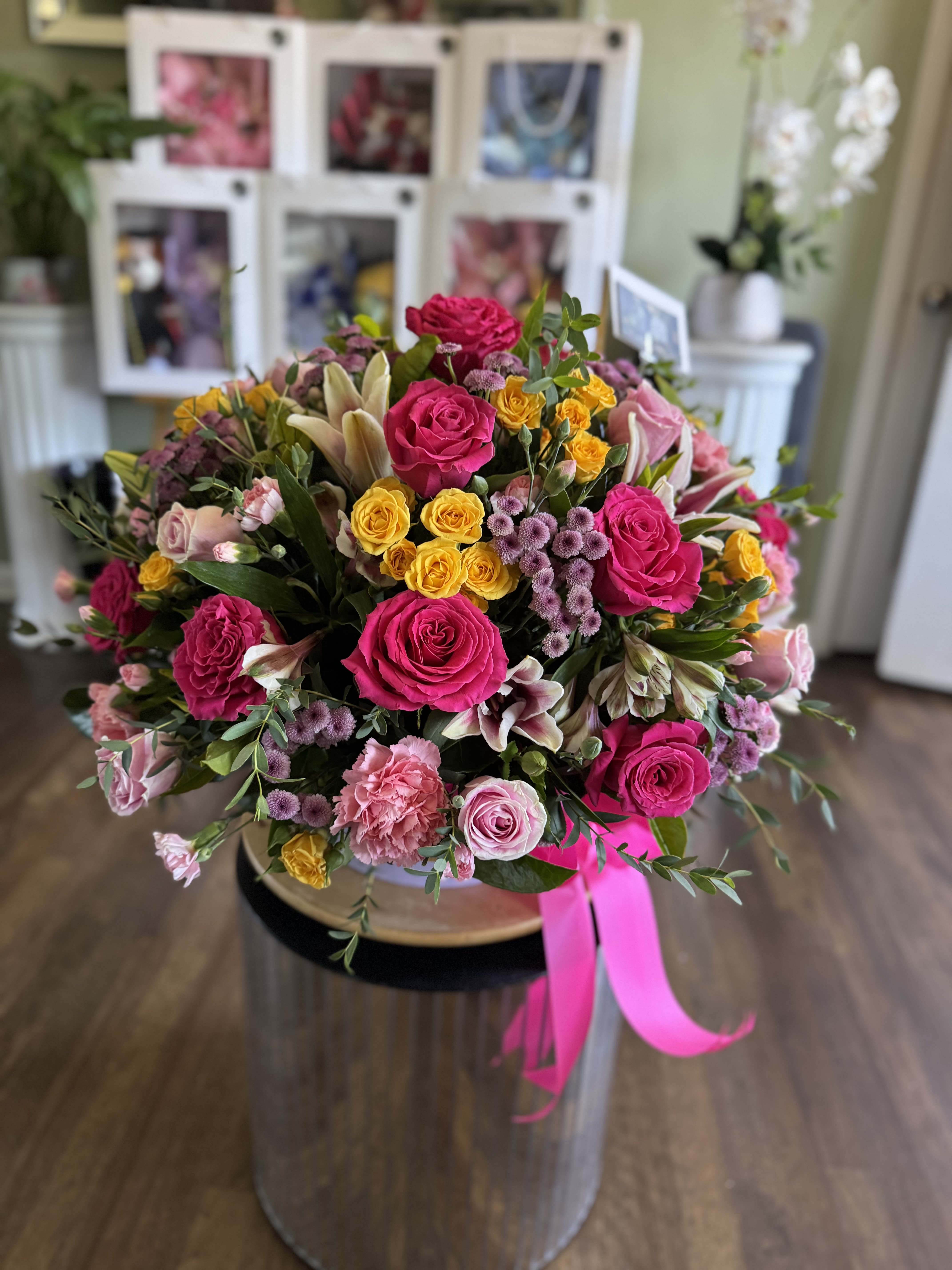 Large bouquet of pink, yellow, and white flowers with a pink ribbon