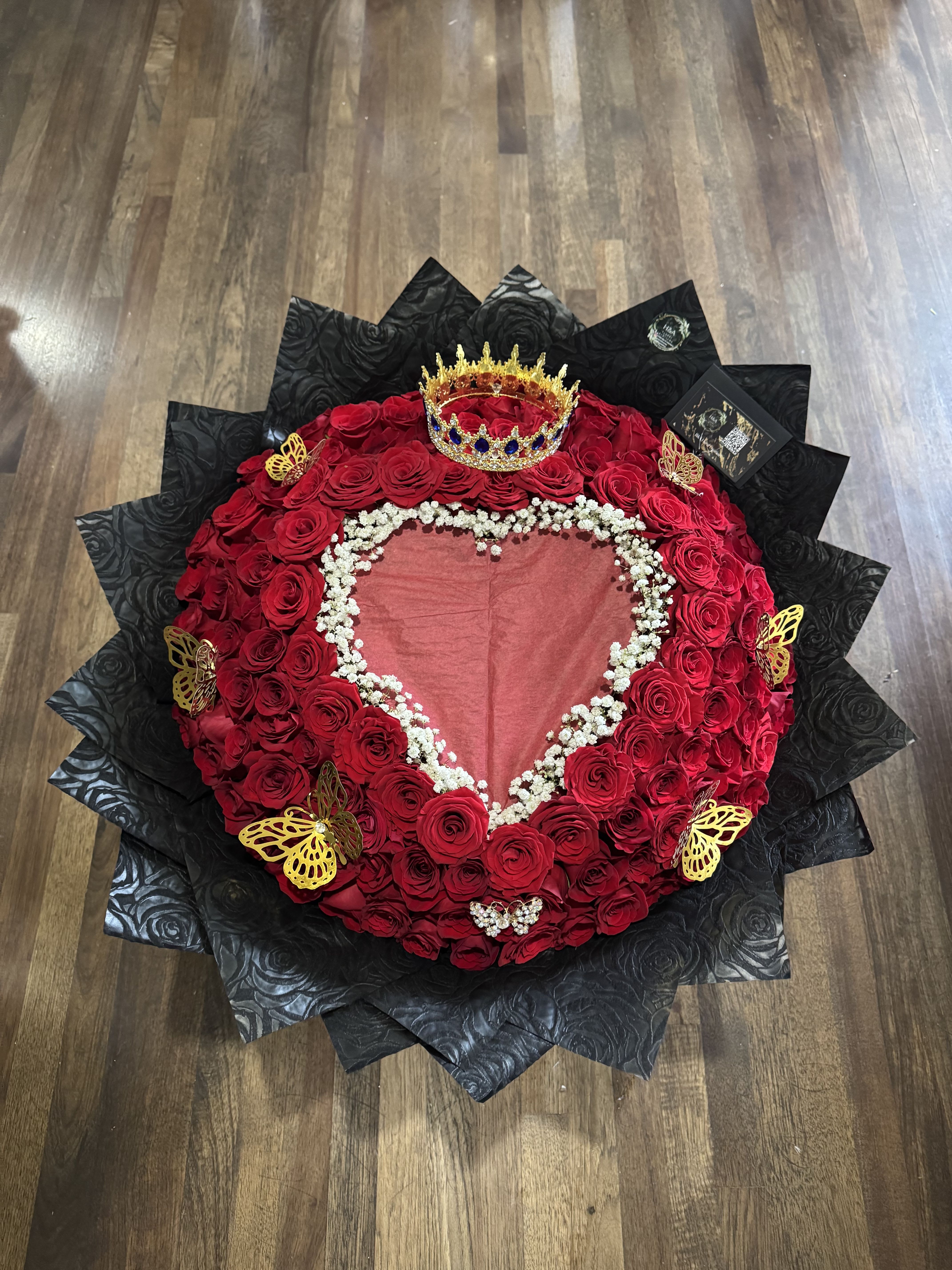 Heart-shaped red rose arrangement with a crown and black wrapping