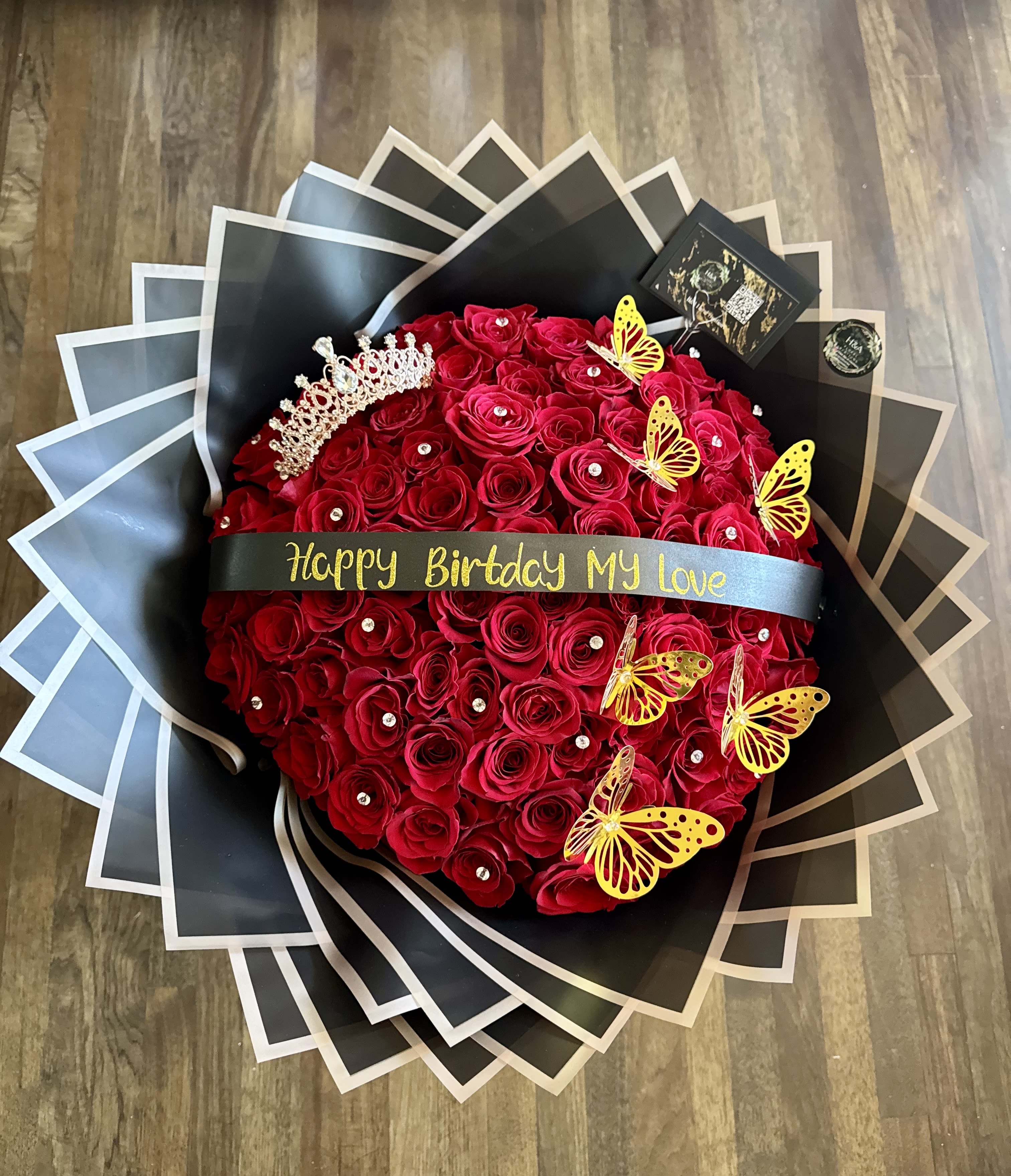Round bouquet of red roses with a birthday ribbon and butterfly decorations