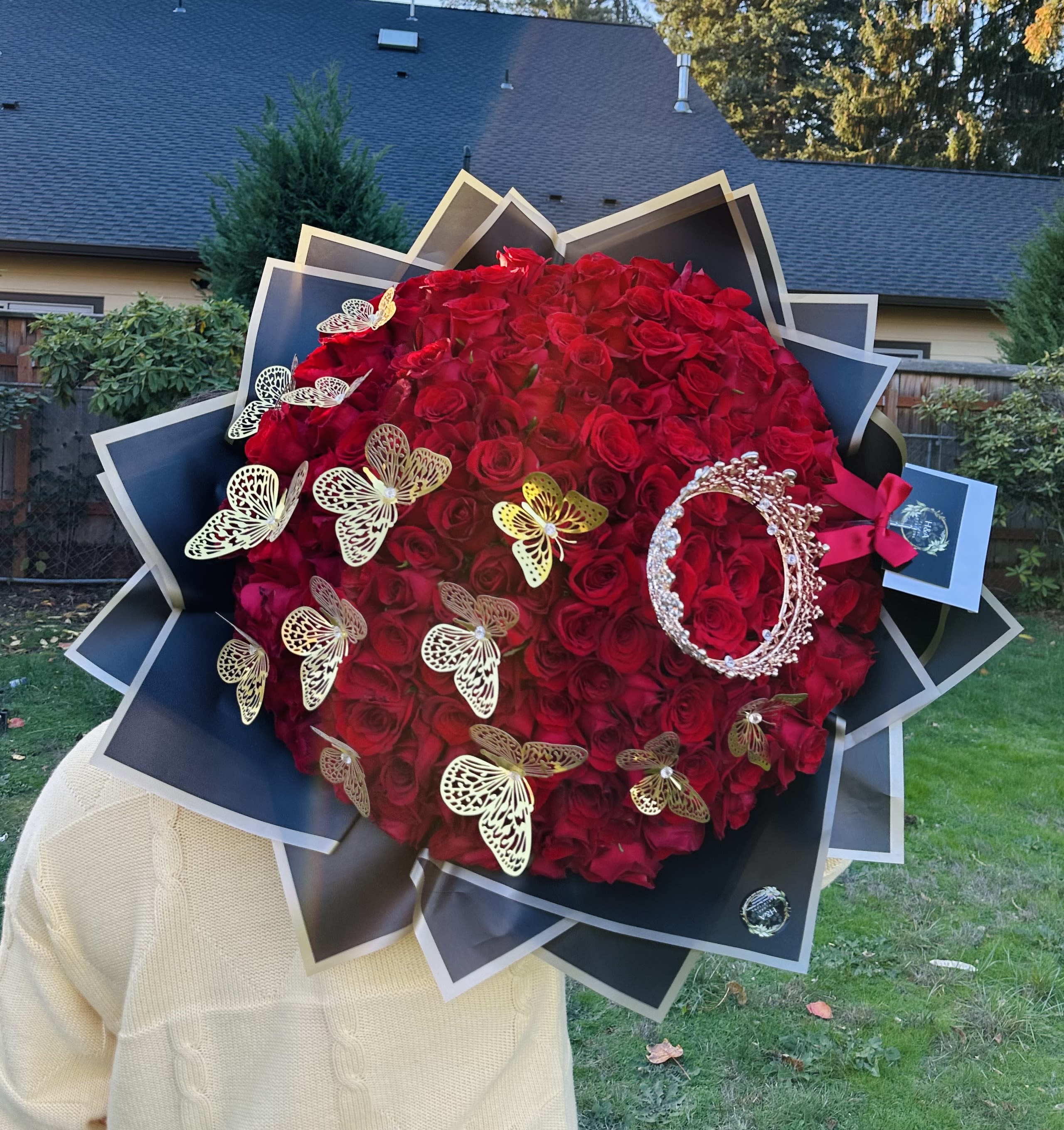Large bouquet of red roses with butterfly decorations and black wrapping