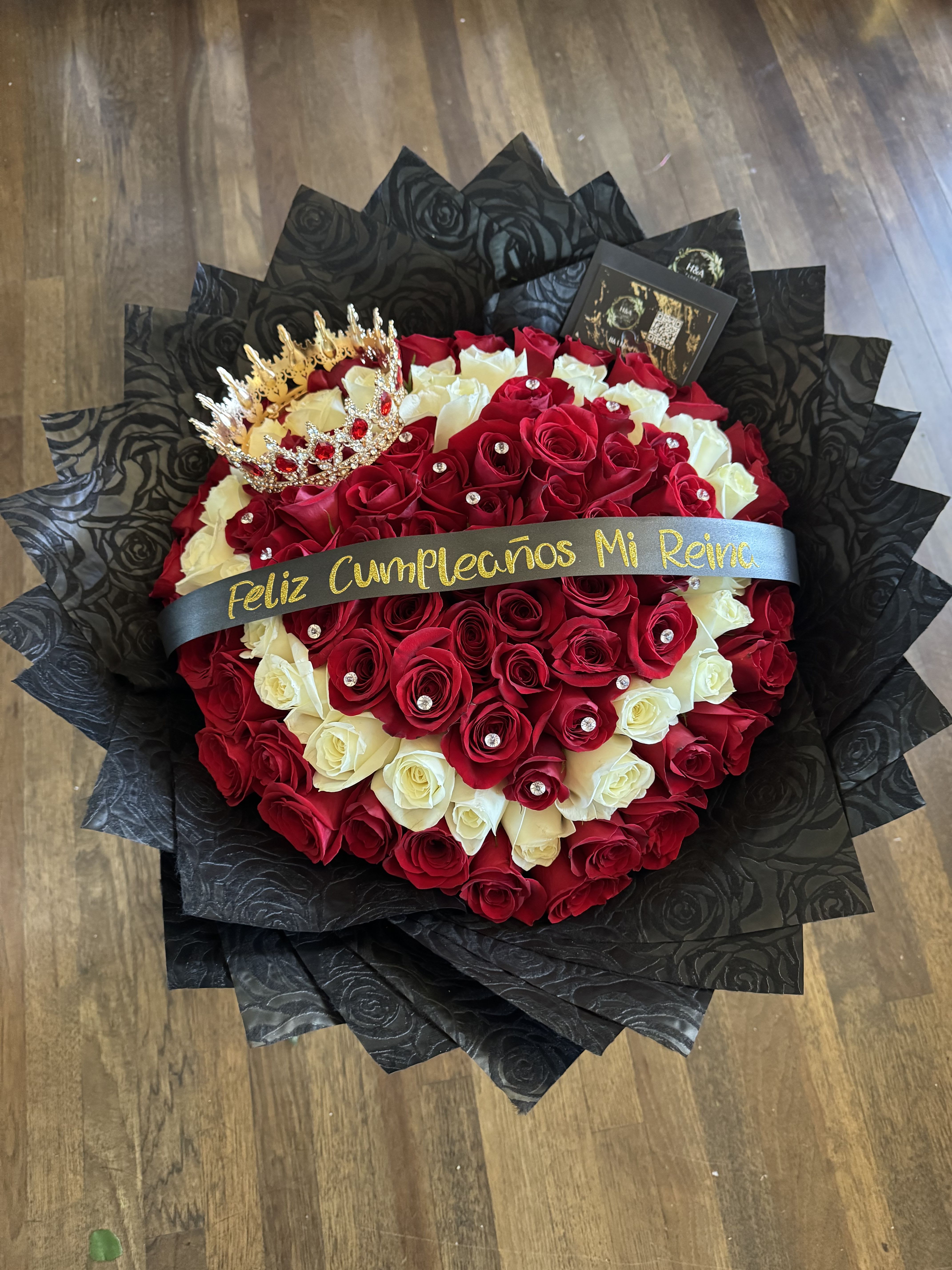 Heart-shaped bouquet of red and white roses with a crown topper