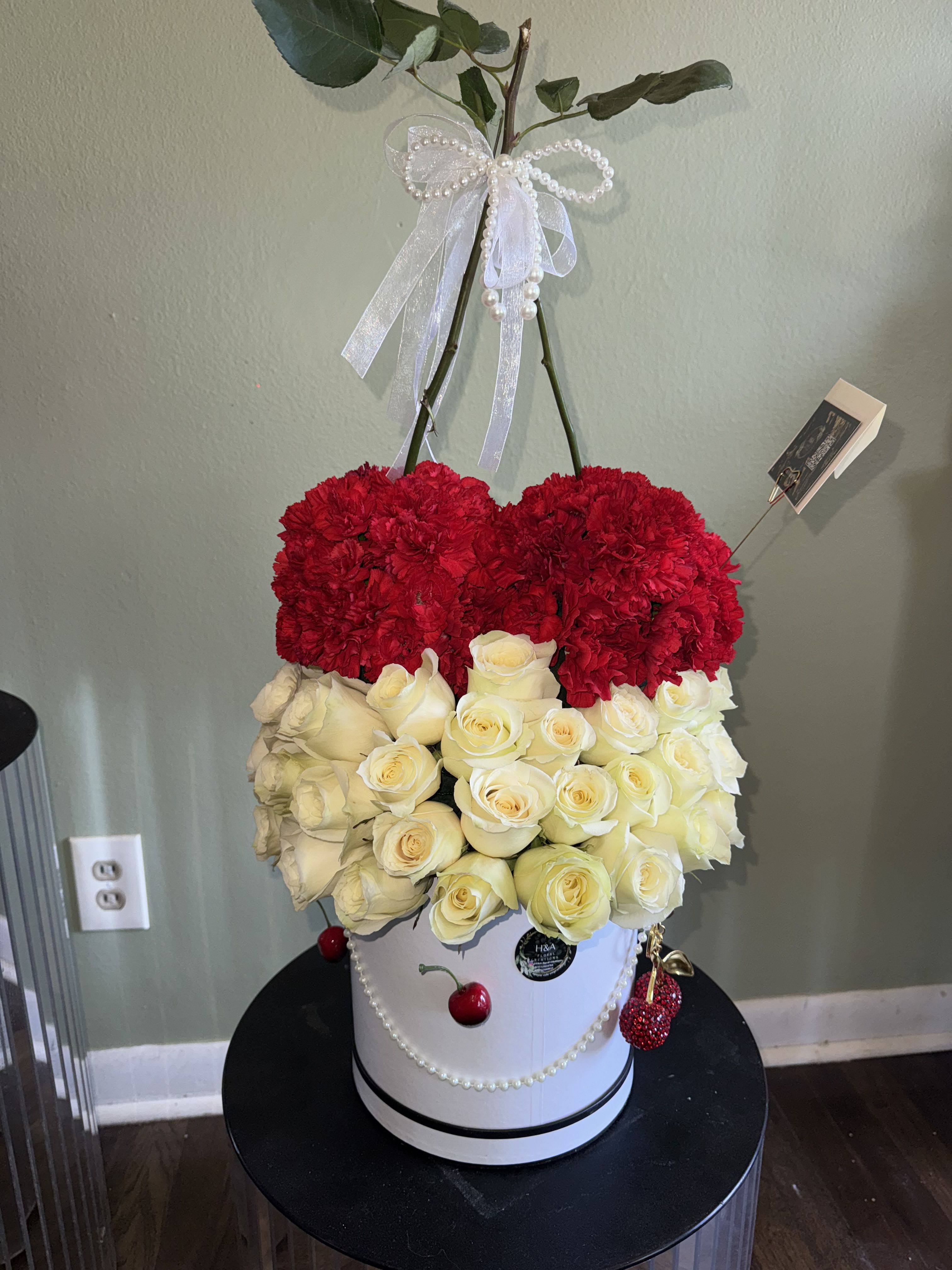 Red carnations and white roses in a white hatbox with pearl ribbon