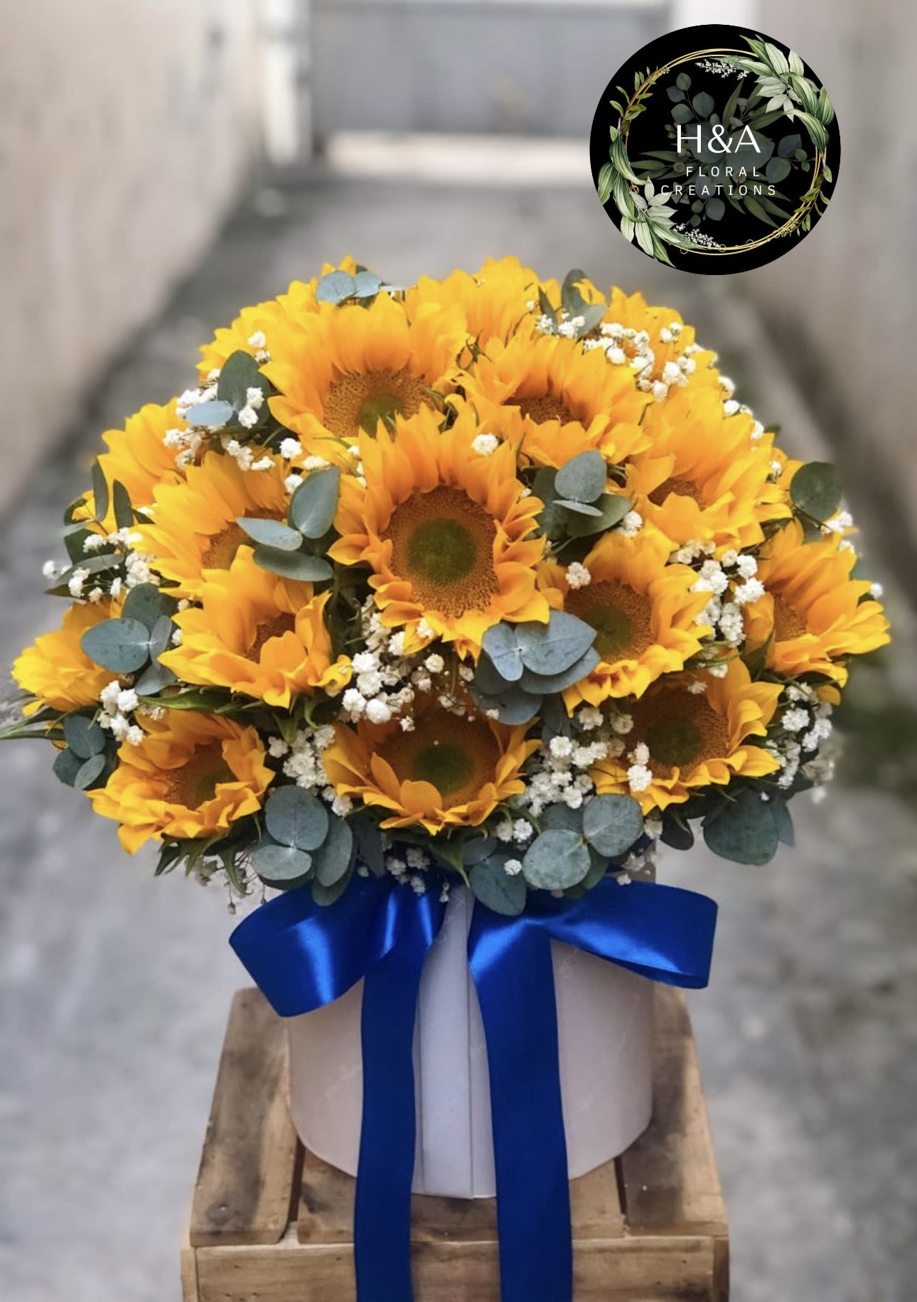Bouquet of yellow sunflowers with blue ribbon in a white box