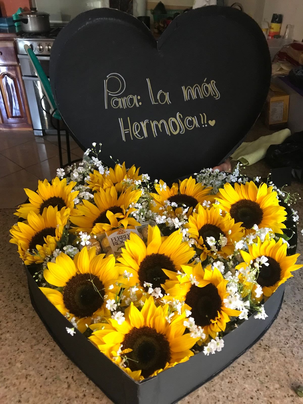 Heart-shaped box of sunflowers with a handwritten message on the lid