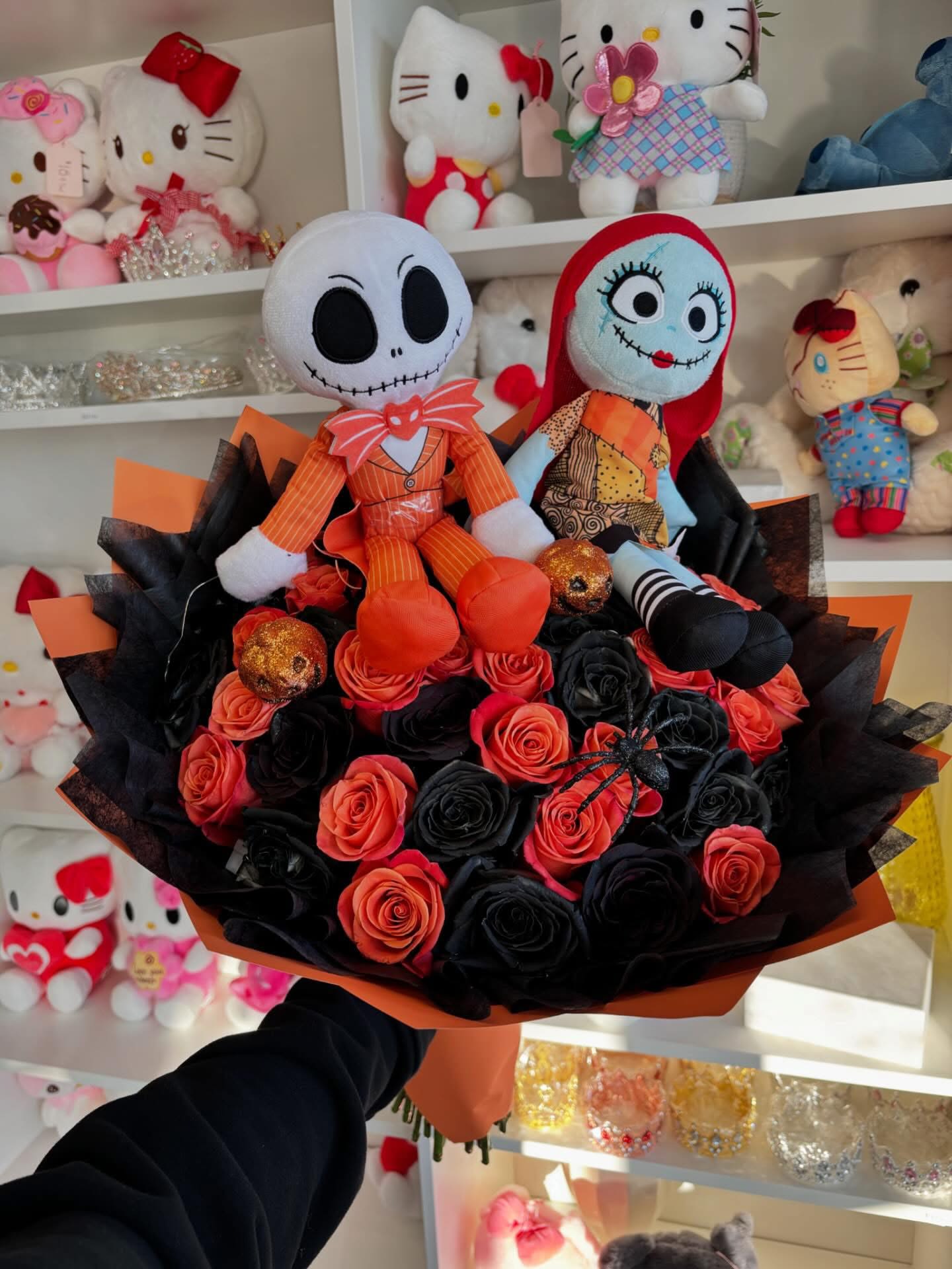 Bouquet of black and orange roses with two plush dolls on top