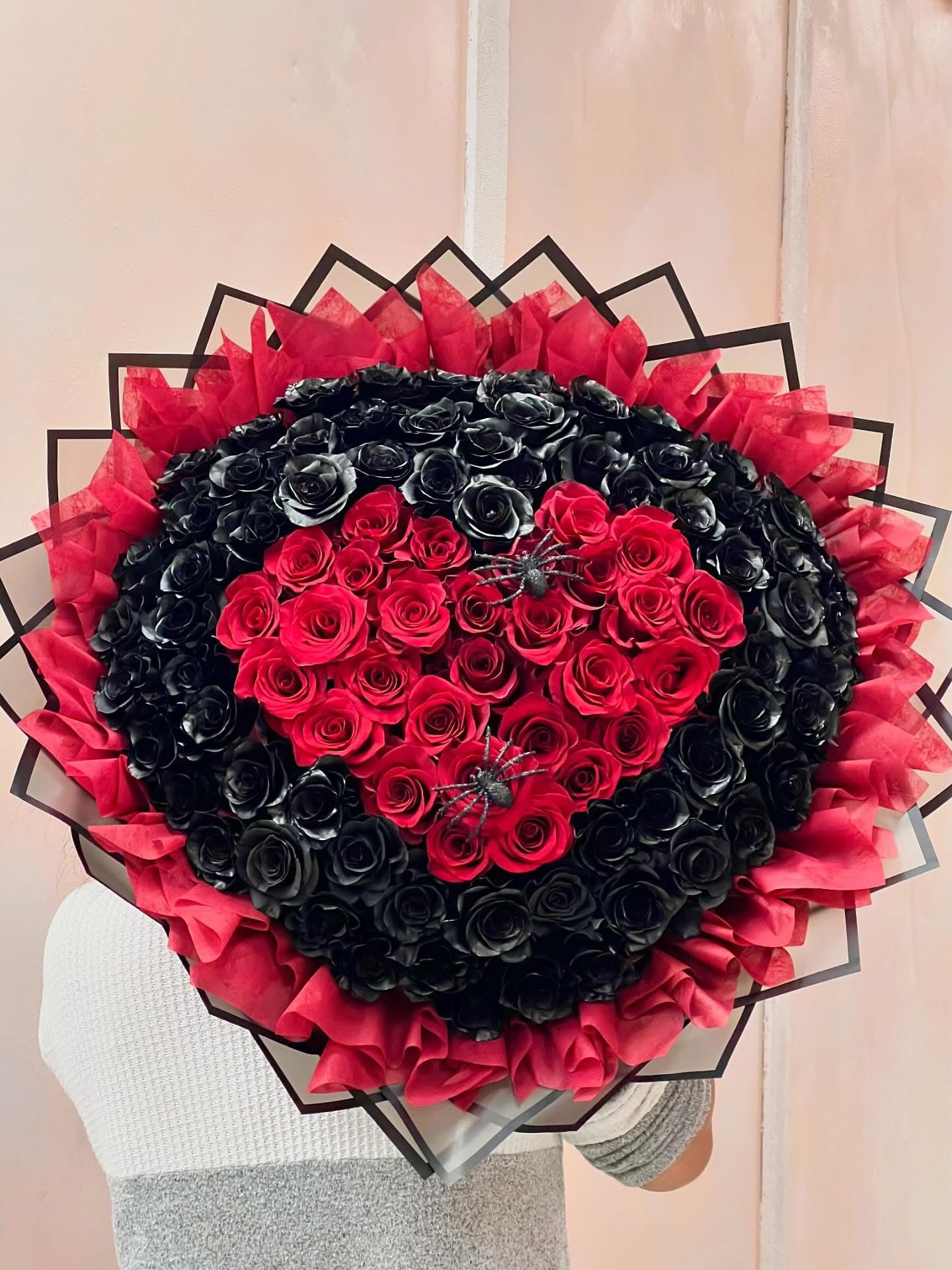 Heart-shaped bouquet of red and black roses with red tissue wrap