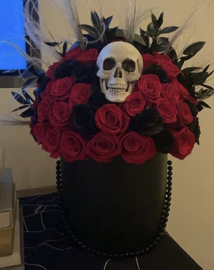 Black hatbox arrangement with red roses and a skull topper