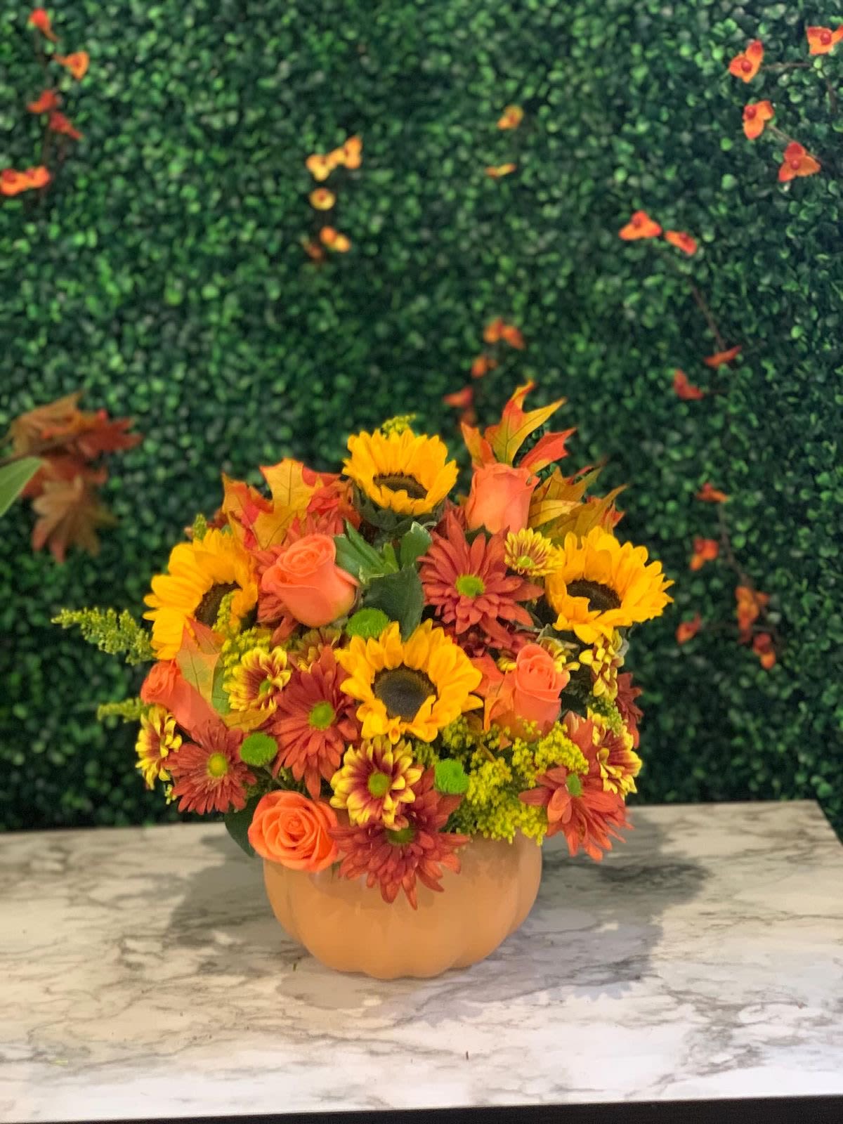 Autumn bouquet of sunflowers, roses, and mums in a pumpkin vase
