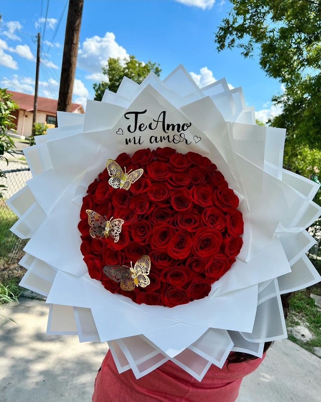 Large bouquet of red roses wrapped in white paper with butterfly accents