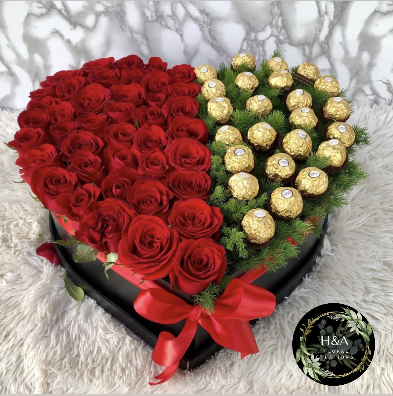 Heart-shaped box of red roses and gold-wrapped chocolates with a red ribbon