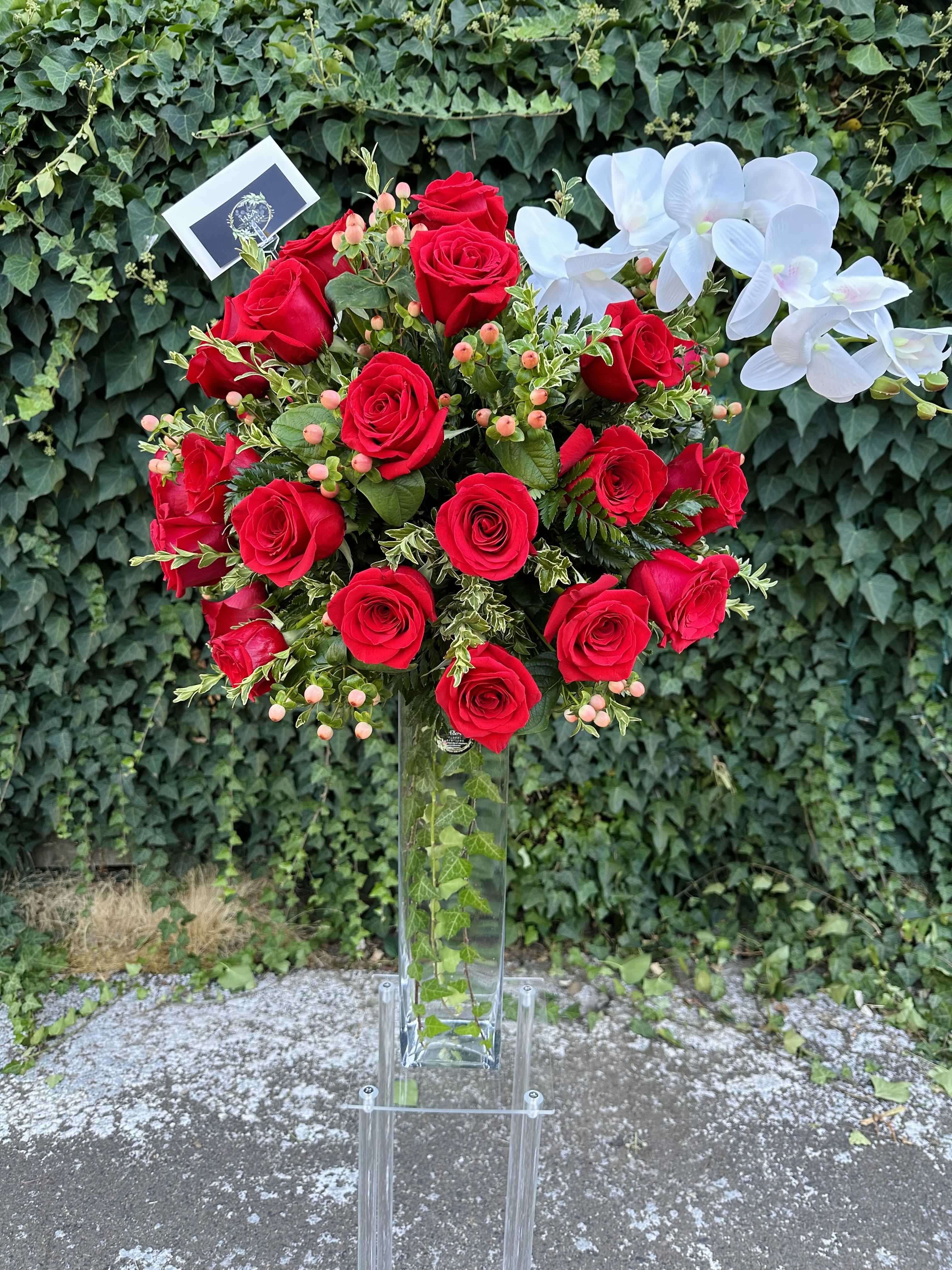 Tall bouquet of red roses with white orchids in a clear vase