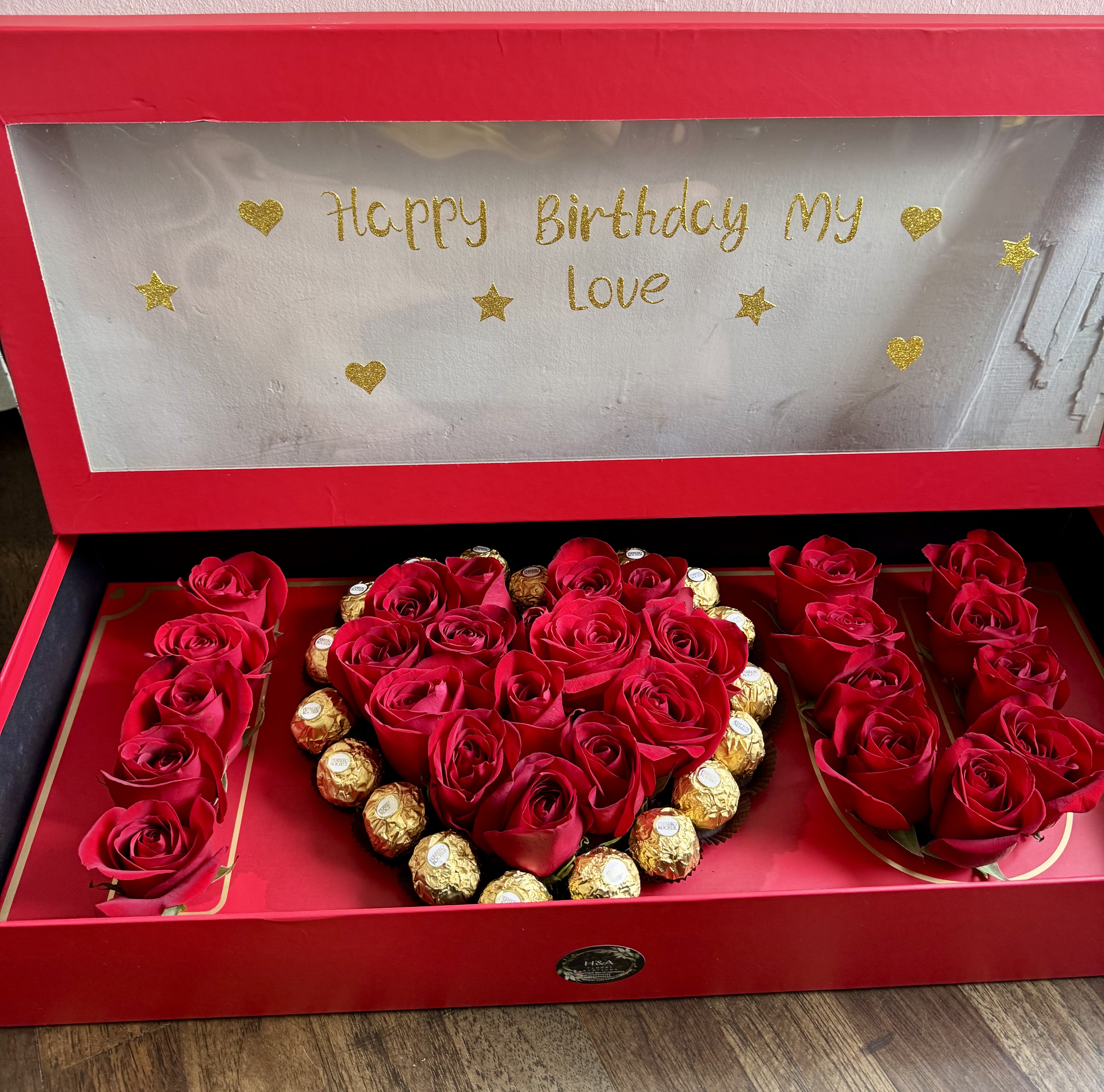 Red roses and chocolates arranged in a heart-shaped gift box