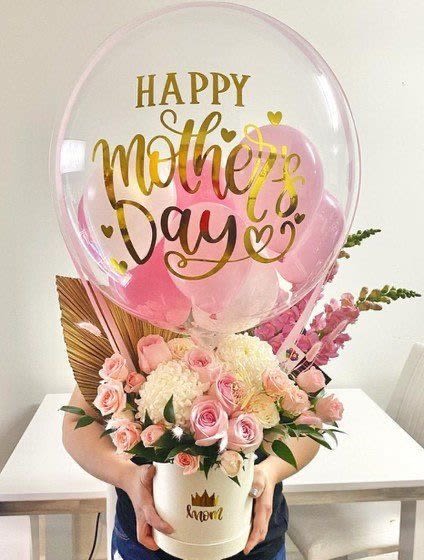 Maternal love flower box  - Celebrate mom with an exquisite arrangement: a luxury base adorned with delicate pastel roses, complemented by seasonal flowers. At the center, a transparent balloon featuring ‘Happy Mother’s Day’, surrounded by pink balloons, brings a chic and festive touch for that special day.”