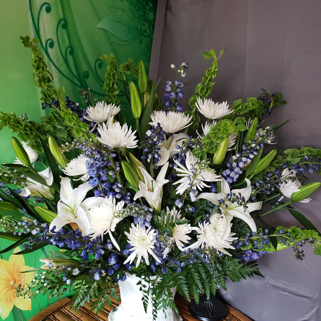 White lilies and chrysanthemums with blue flowers in a white vase