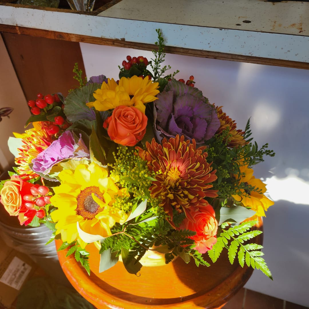 Bright mixed bouquet with sunflowers, roses, and purple cabbage in a vase