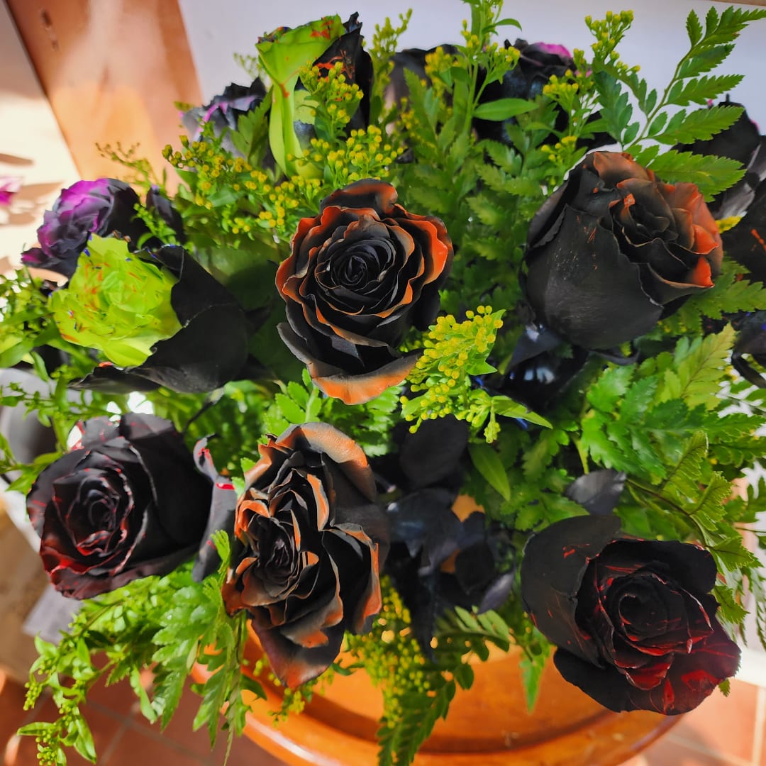 Bouquet of black roses with orange edges and bright green filler