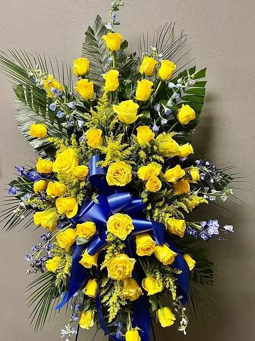 Tall yellow rose standing spray with blue ribbon and palm fronds