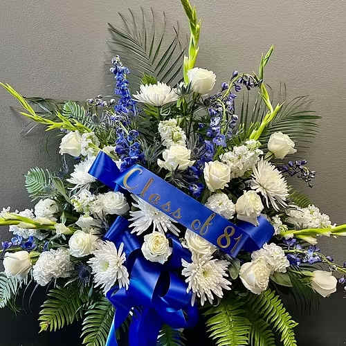 White and blue funeral spray with a blue ribbon reading "Class of 81"