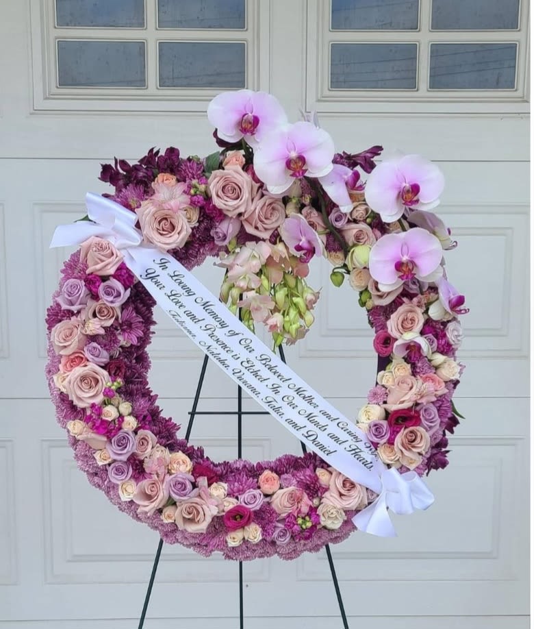 Heart-shaped floral wreath with pink roses and orchids on an easel