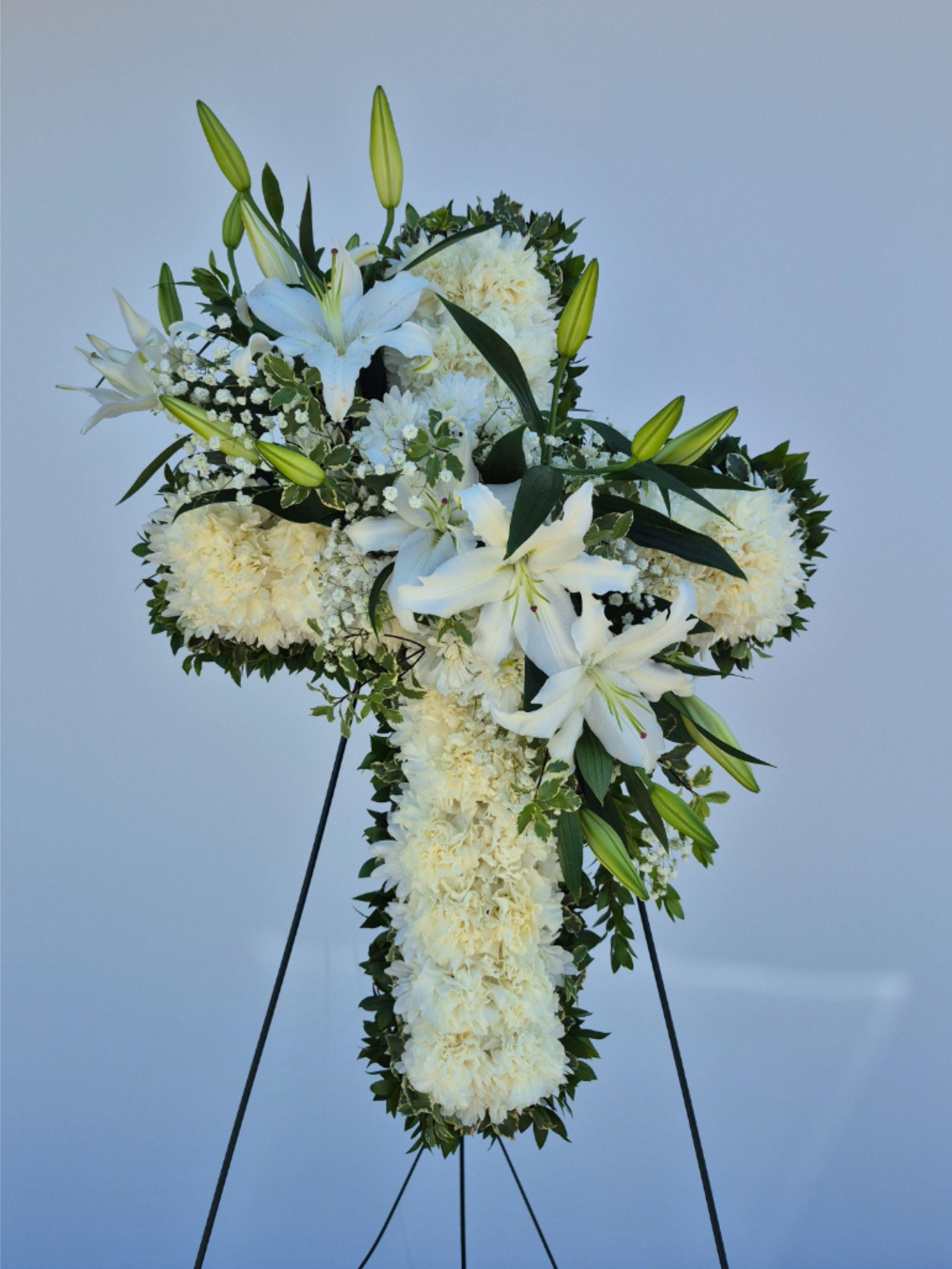 Heavenly Cross  - The cross made with beautiful white carnations with bloomed oriental lilies in the center. A sunning choice to honor your loved one.  We include easel, printed banner, and delivery (some fees may apply). Additional banner can be added for $40.  Standard- Approximately 16"W x 22 H" Deluxe - Approximately 18"W x 26" H Premium- Approximately 20"W x 30"H  Available Height Size: 22", 26", or 30" 