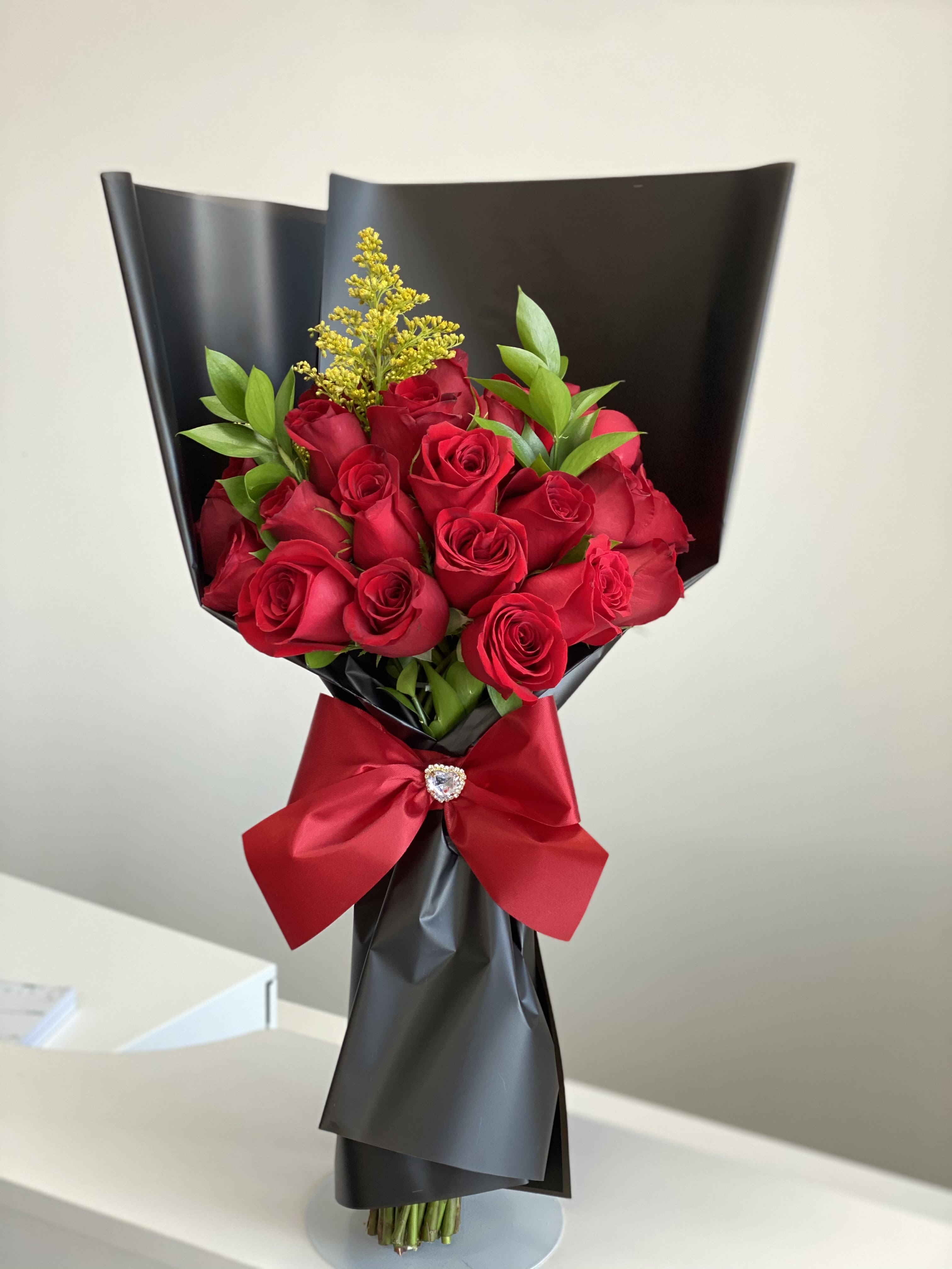 Bouquet of red roses wrapped in black paper with a red ribbon