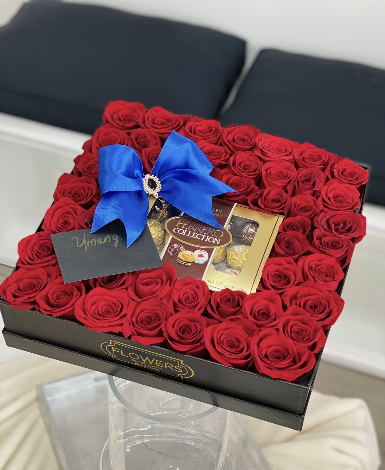 Box of red roses with a blue bow and chocolates