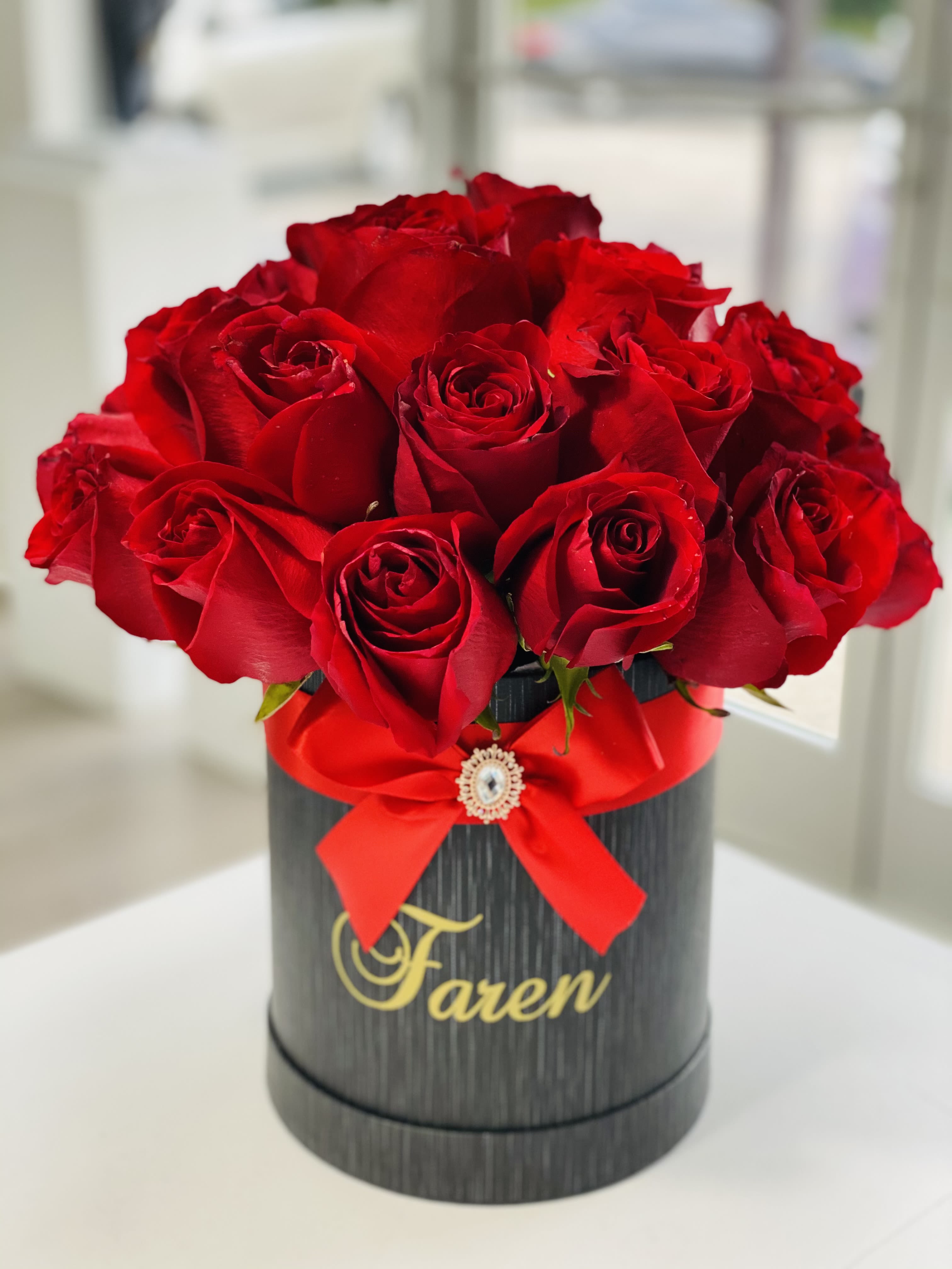 Red roses arranged in a black round box with a red ribbon
