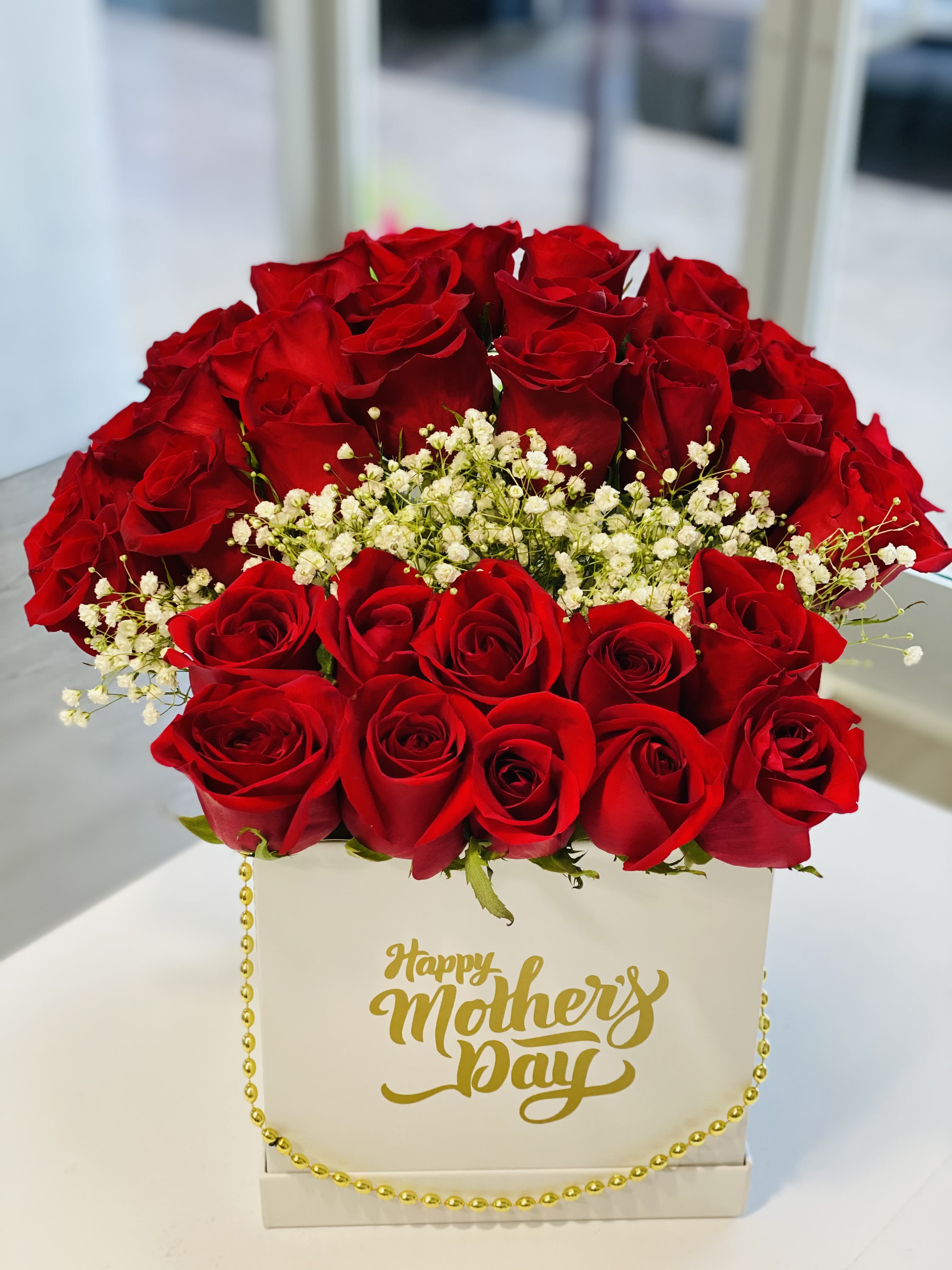 Red roses arranged in a white box with a gold Happy Mother's Day message
